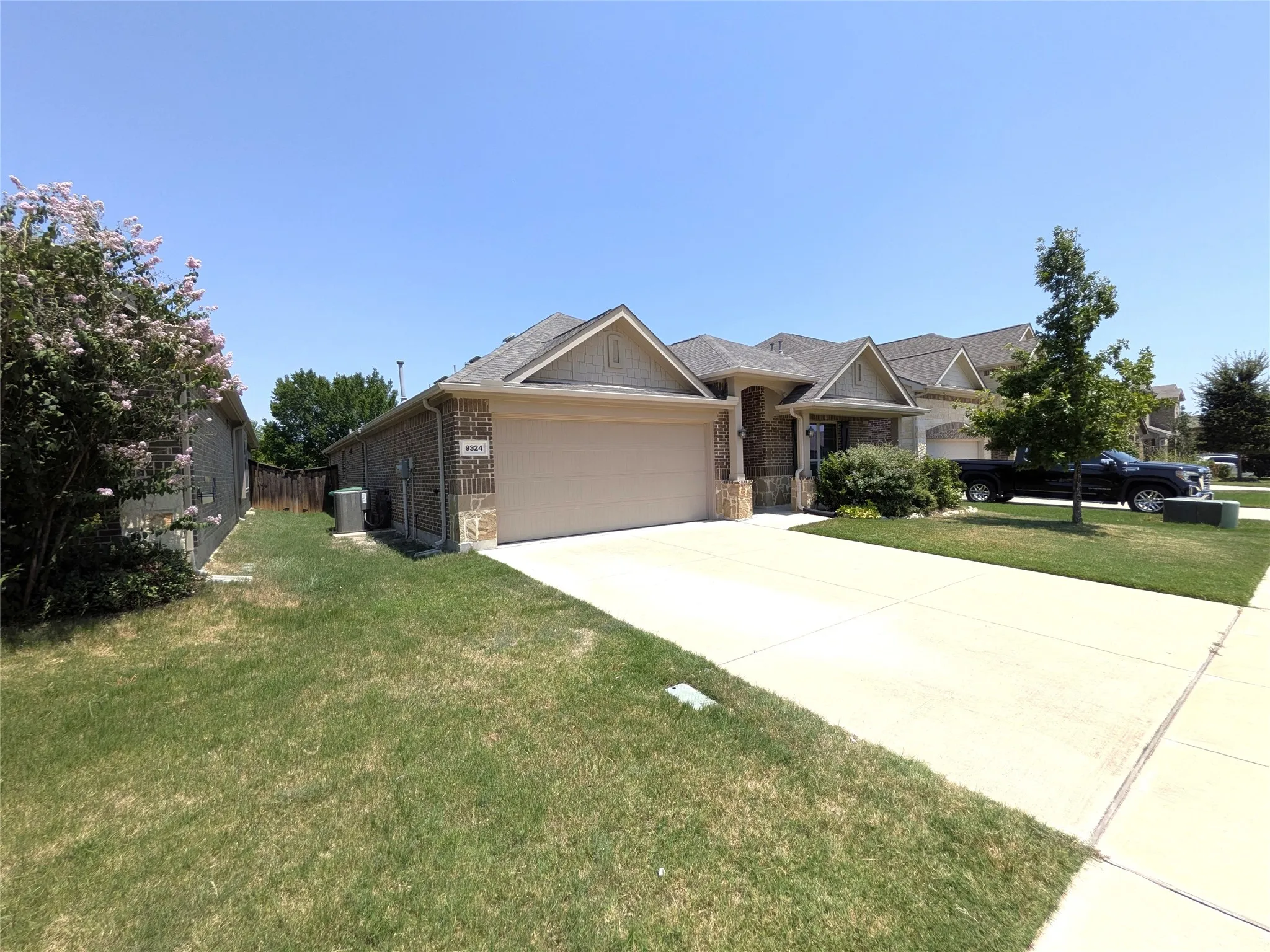 Traditional-style exterior featuring brick and stone accents, a two-car garage, and a concrete driveway
