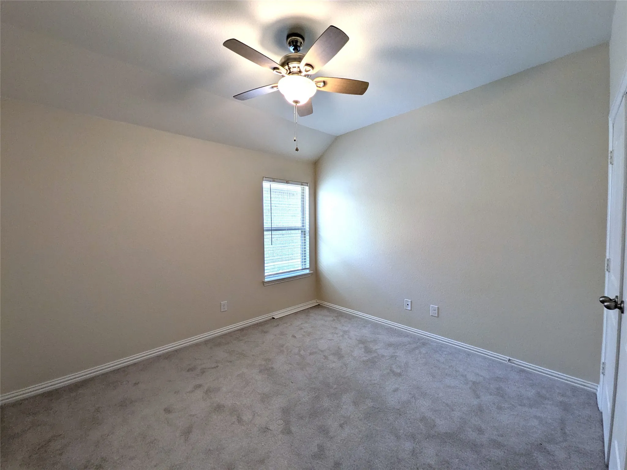 Carpeted room featuring a ceiling fan with light fixture, a window with horizontal blinds, and neutral wall paint