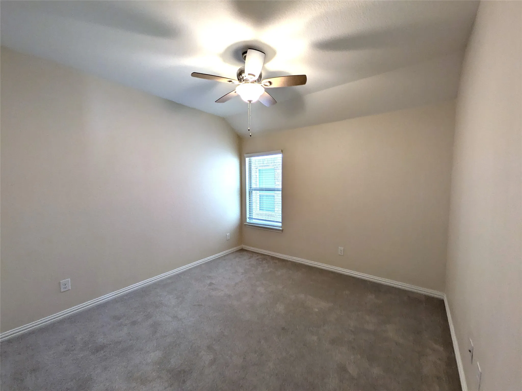 Carpeted room with a ceiling fan light fixture, sloped ceiling, and window with blinds