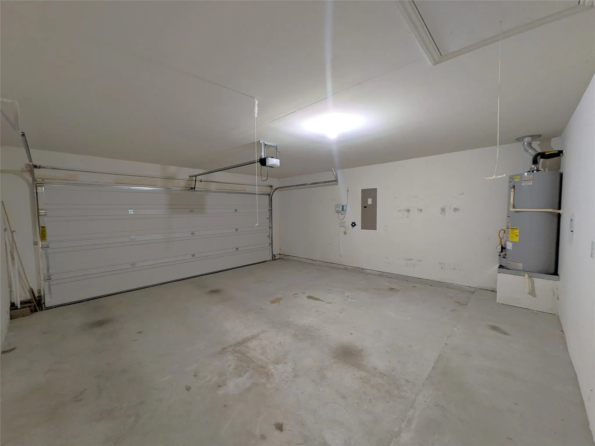 Spacious garage with a sectional overhead door, concrete flooring, and an exposed water heater