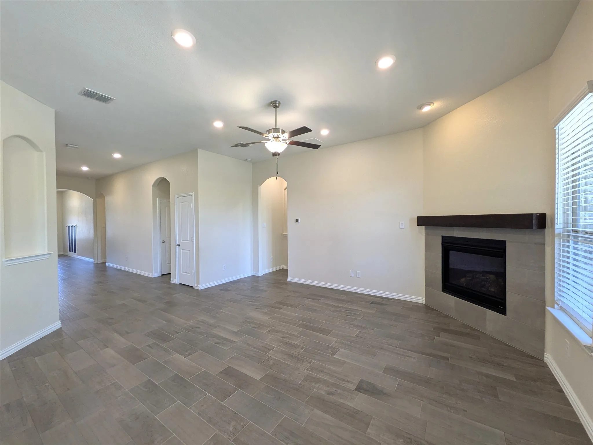 Spacious living area featuring plank-style tile flooring, recessed lighting, and a ceiling fan