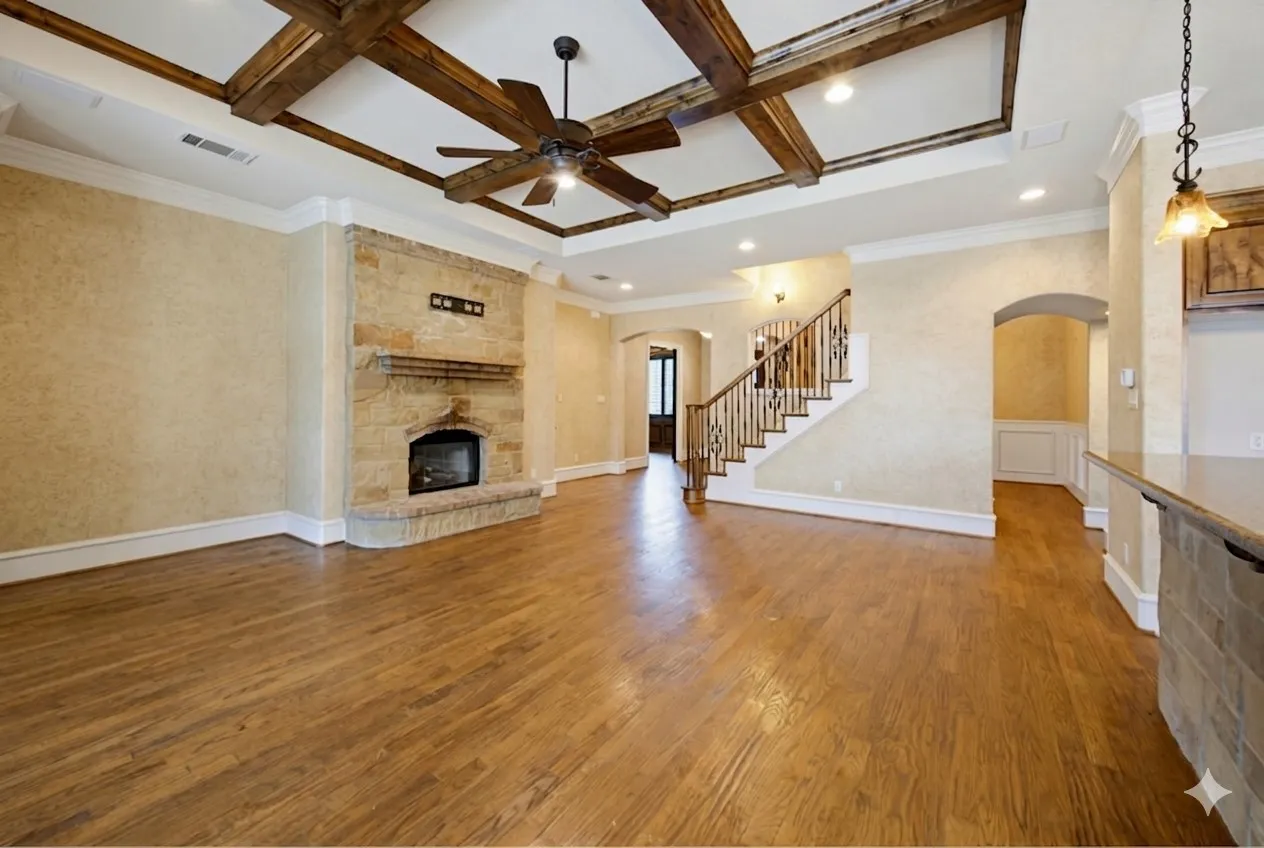 Spacious open-concept living area showcasing rich wood-finish flooring, decorative exposed ceiling beams with recessed lighting, and a stone fireplace with integrated hearth