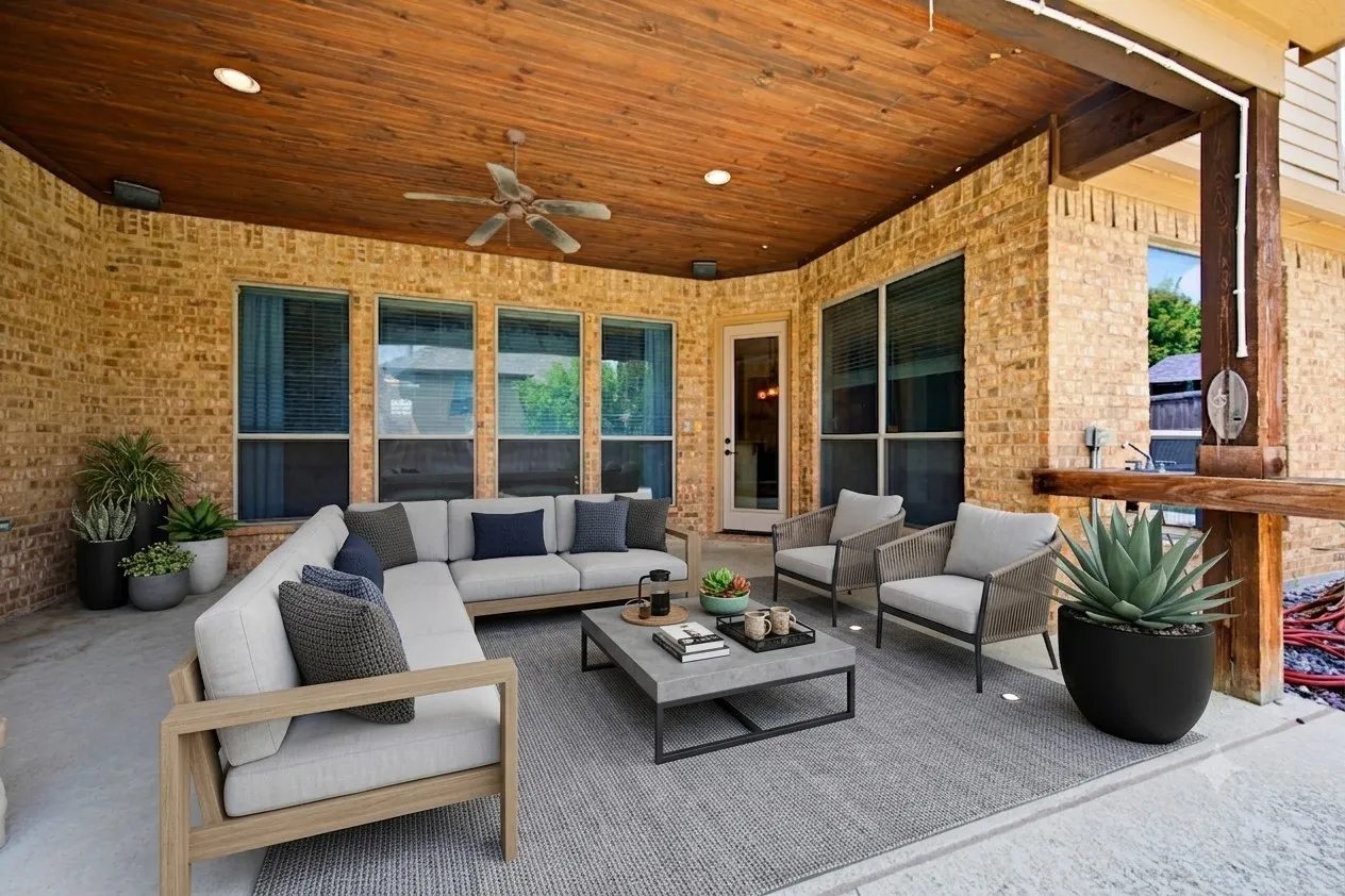 Virtually staged patio furniture. Spacious covered patio featuring a wood-finish ceiling with recessed lighting and a ceiling fan, brick exterior walls, and multiple large windows