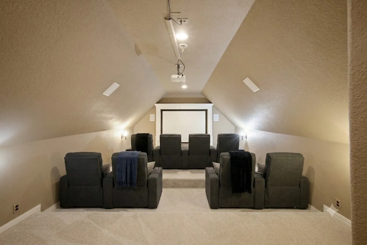 Virtually staged. Dedicated home theater featuring a projection screen, built-in speakers, recessed lighting, and wall sconces