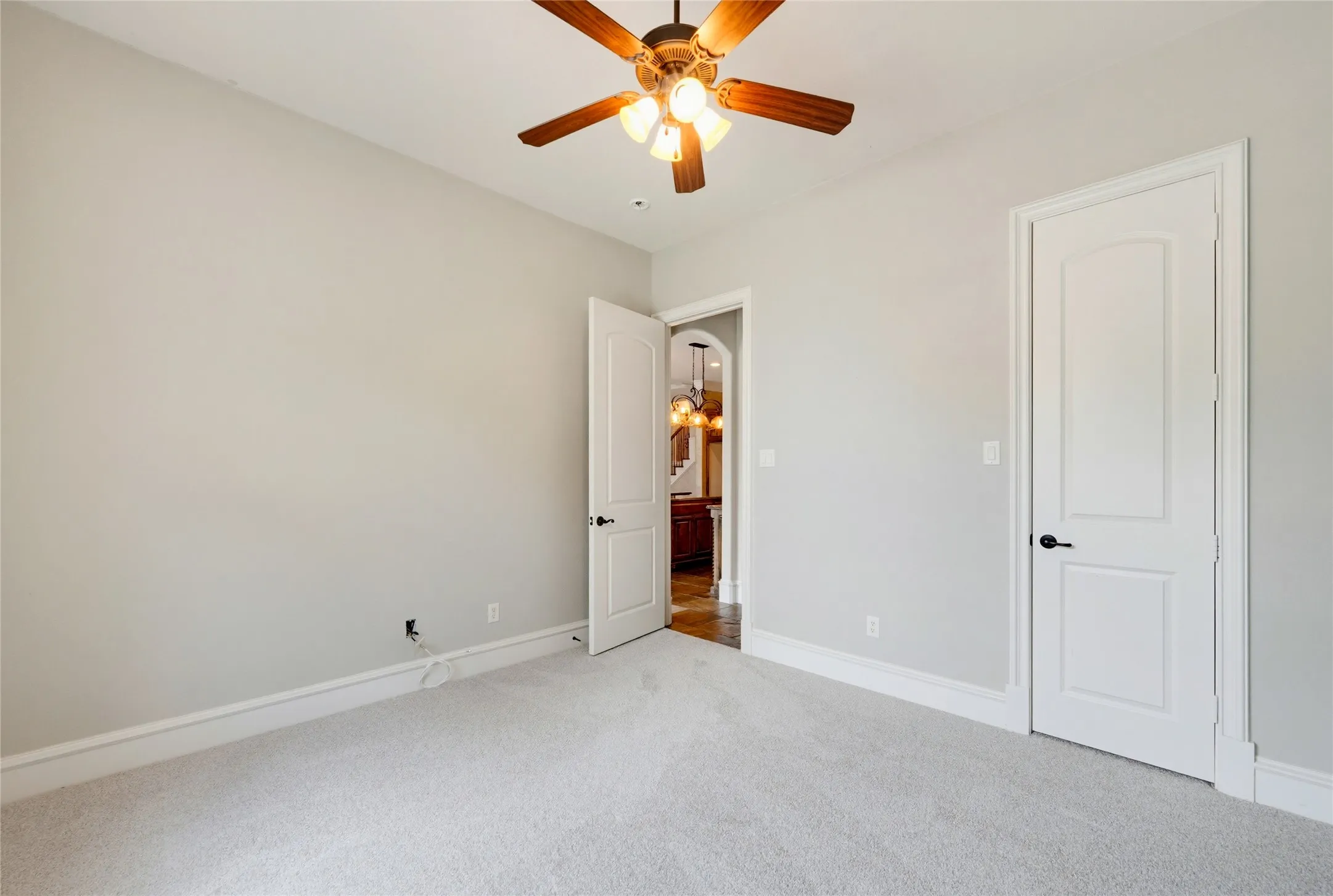 1st level guest suite  Spacious bedroom featuring neutral wall finishes, plush carpeting, ceiling fan with integrated lighting, and dual closet entries with six-panel doors