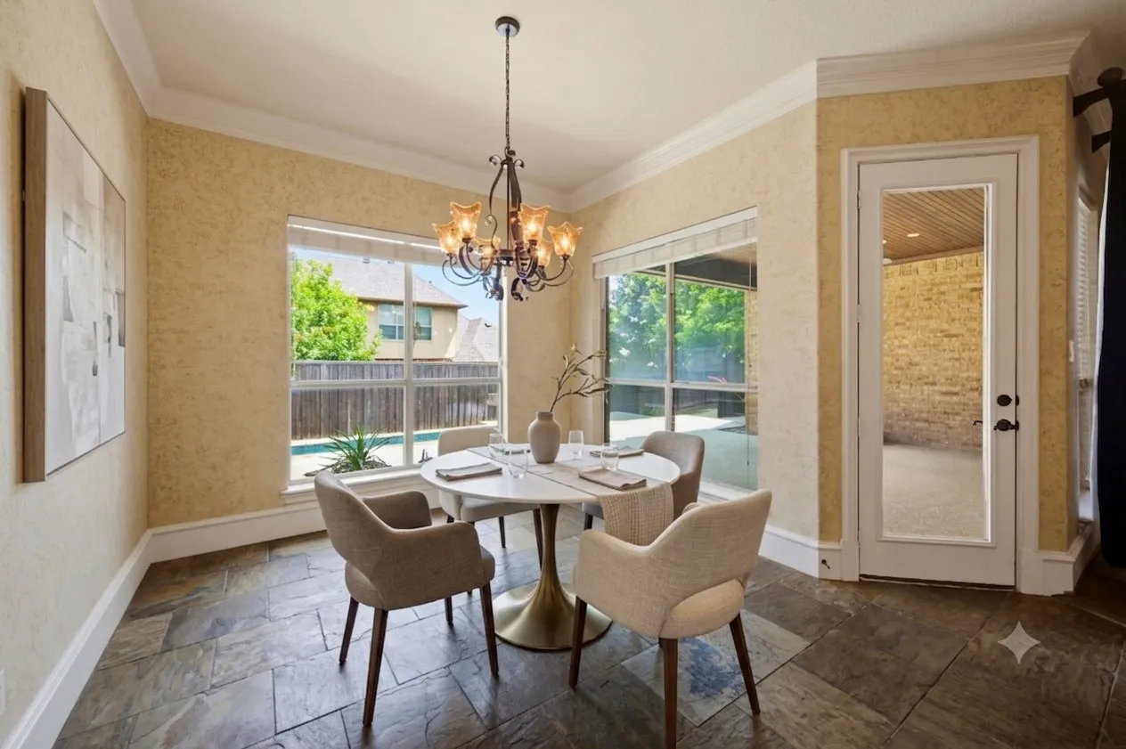 Virtually staged. Interior dining space featuring natural light, slate tile flooring, crown molding, a decorative chandelier, and a glass-paneled door leading to an outdoor covered patio