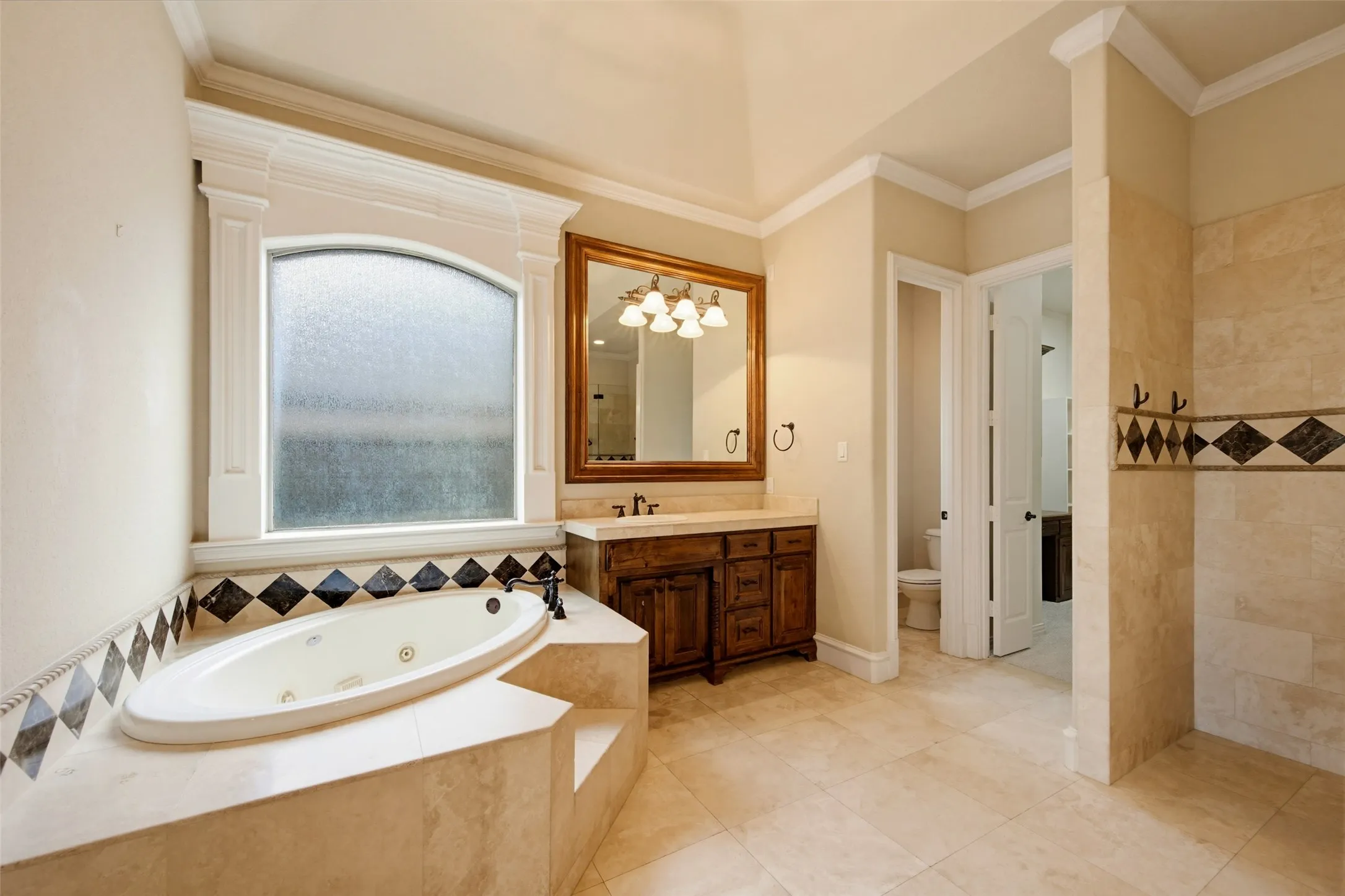 Spa-inspired master bathroom featuring a corner soaking tub with surround, dual vanity with wood cabinetry and framed mirror, decorative tile accents, heated tile flooring, and a spacious walk-in shower with glass enclosure and stone-look tilework