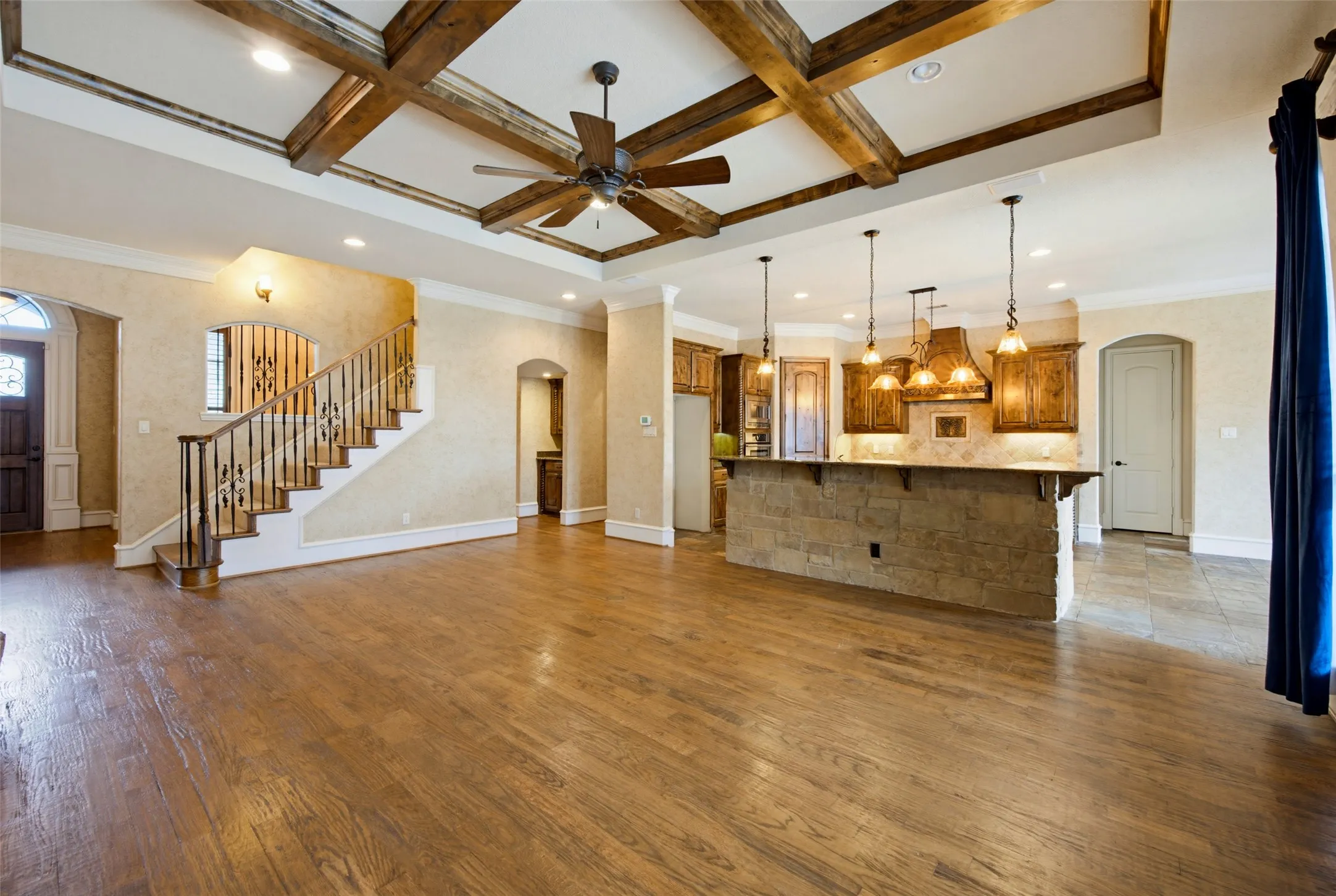 Open-concept great room featuring exposed wooden beam ceiling details, recessed lighting, and wide-plank wood-finish flooring