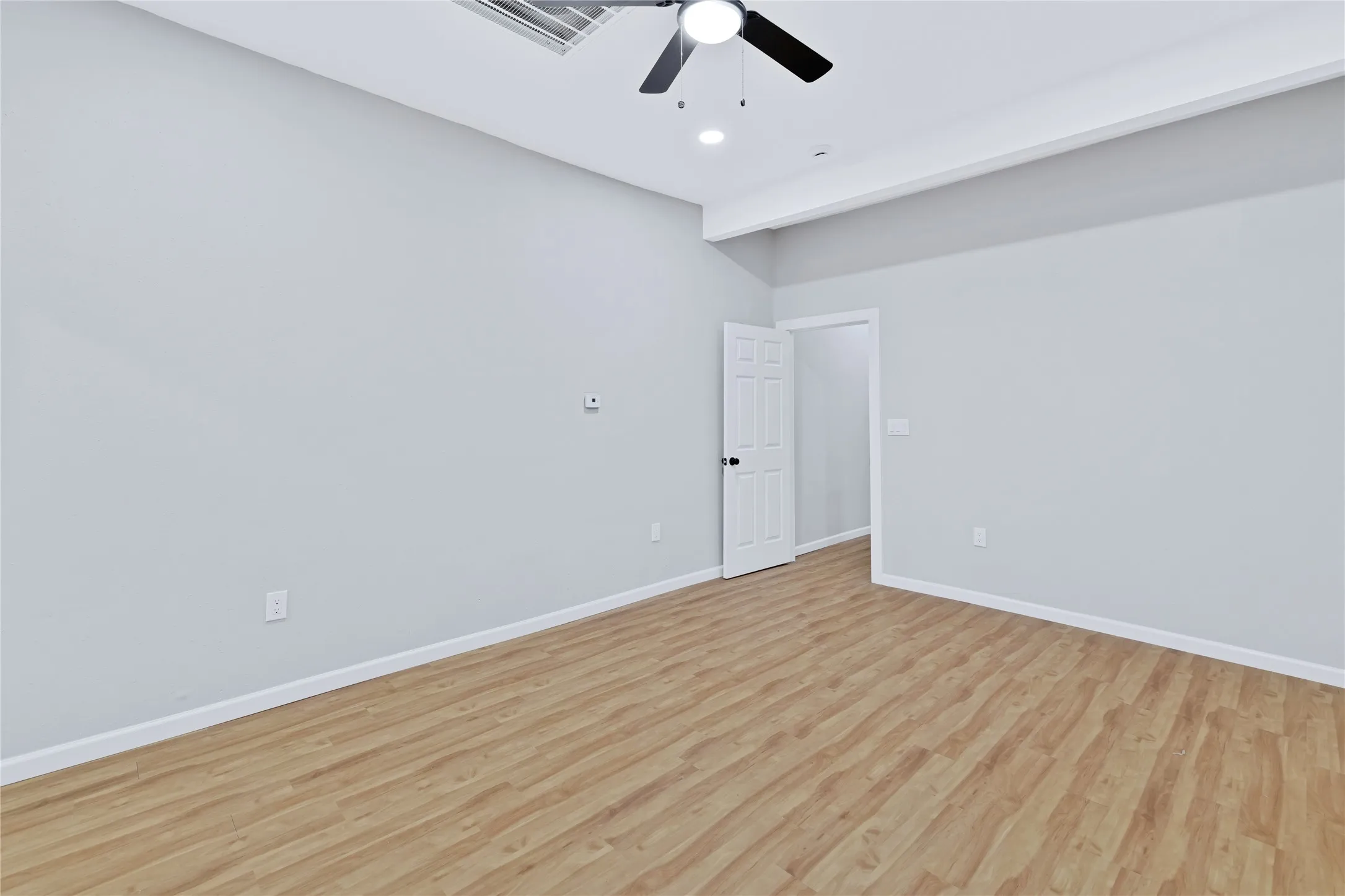 Wood-finish flooring, light grey wall paint, ceiling fan with integrated lighting, recessed lighting, and a white interior door