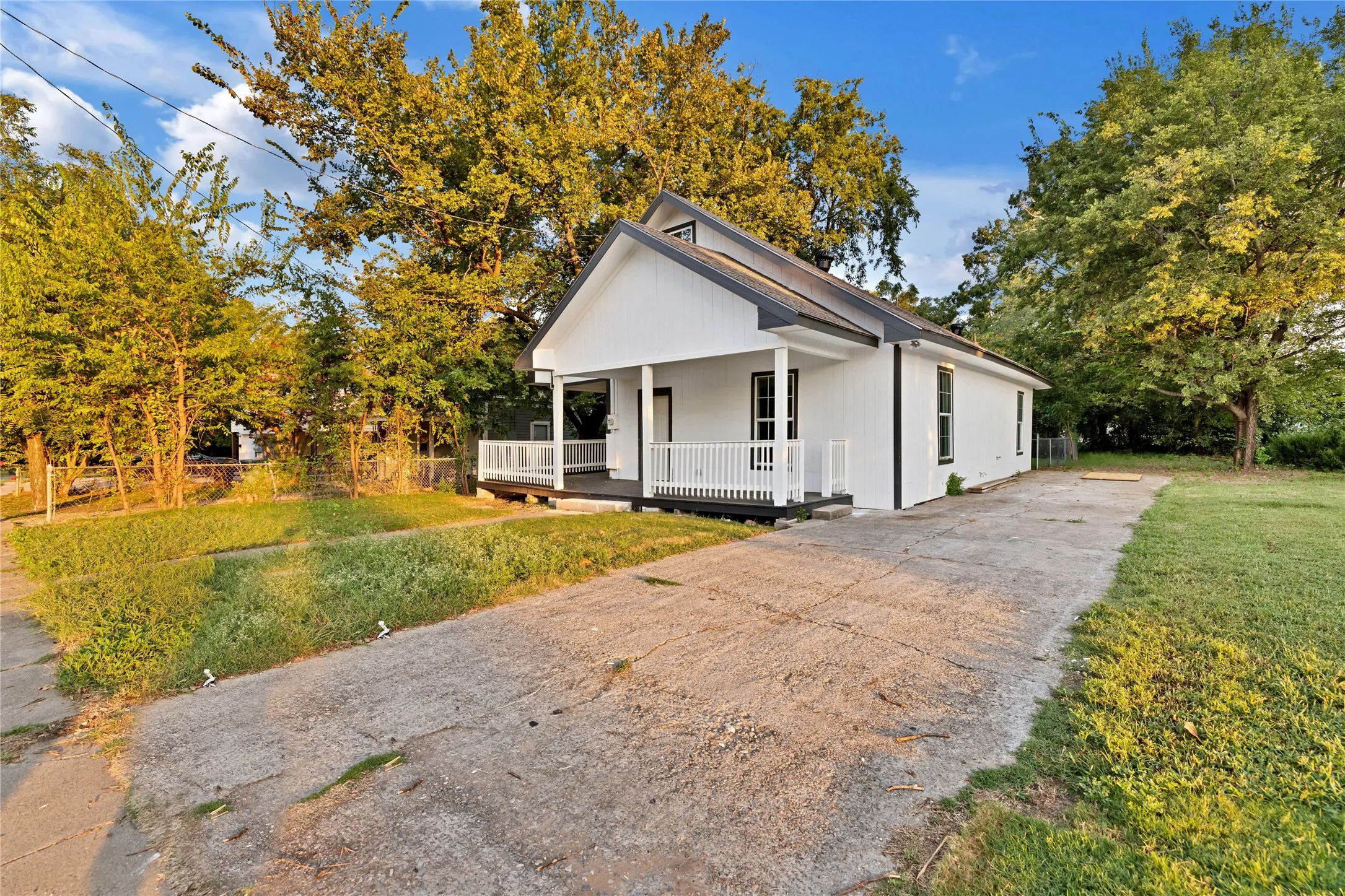 White exterior siding, dark-trimmed windows, covered front porch with white railing, and a gabled roofline
