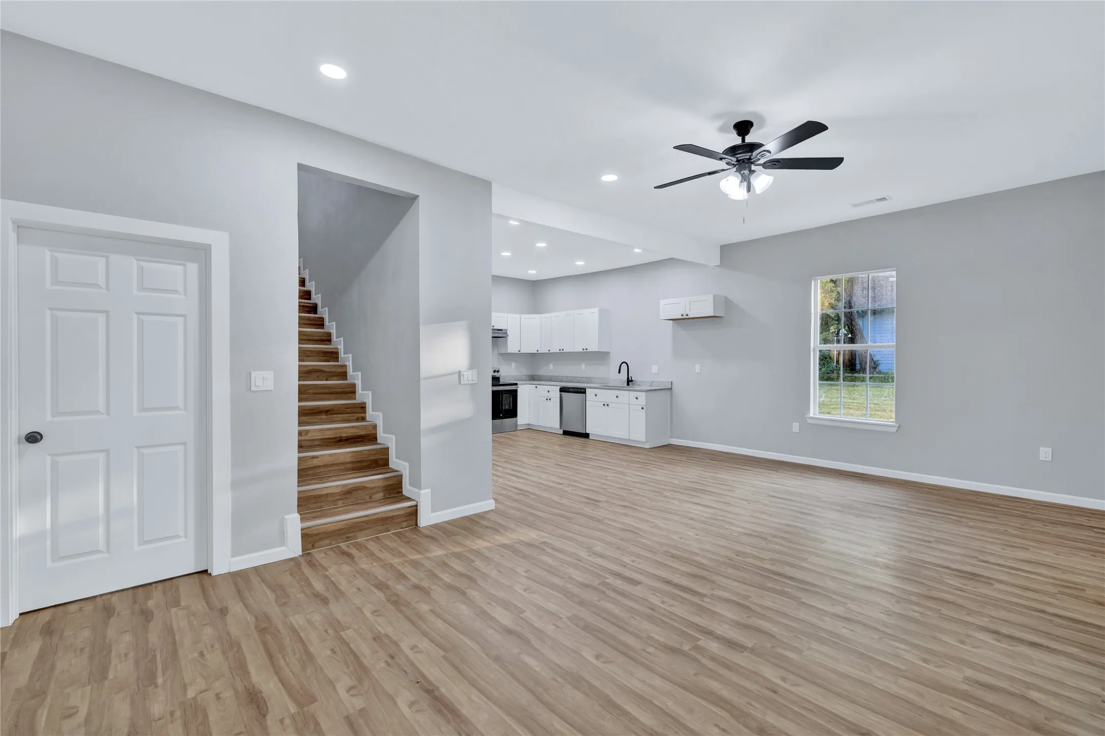Open-concept layout with wood-finish flooring, recessed lighting, and a modern ceiling fan