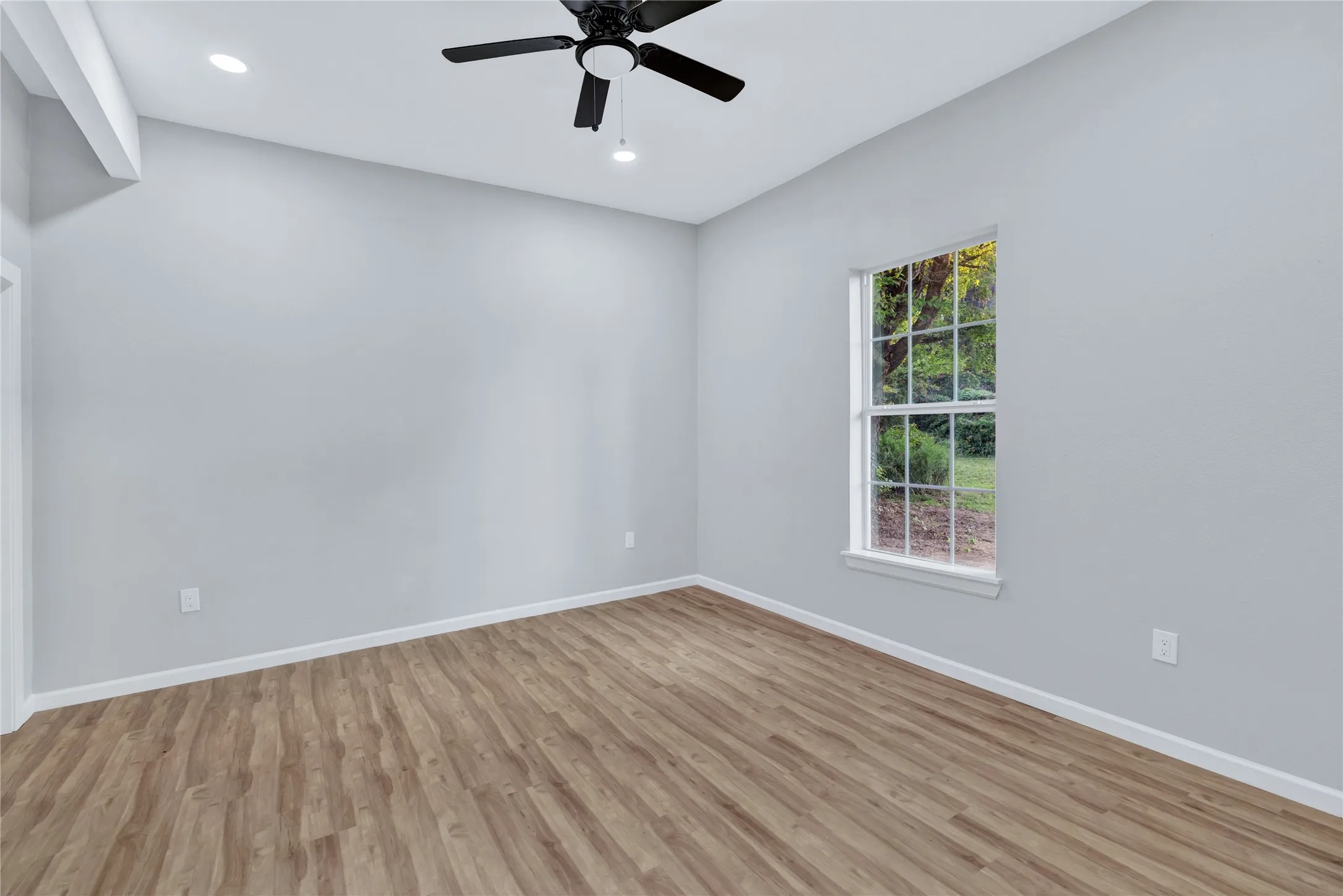 Wood-finish flooring with white trim, recessed lighting, and a ceiling fan