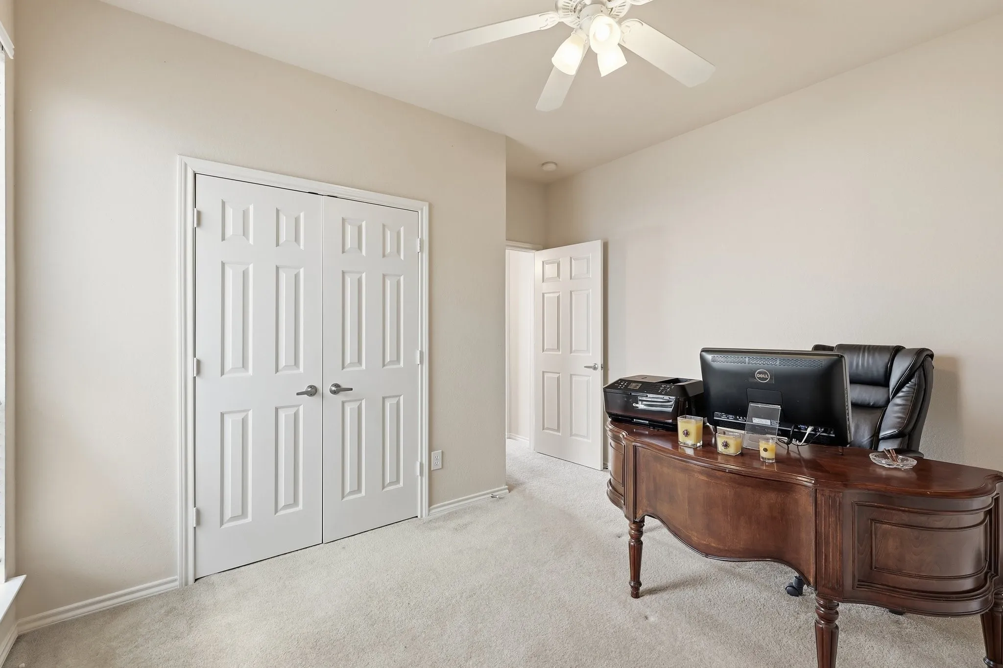 Neutral-toned room featuring a ceiling fan, light-colored carpeting, and a white six-panel bifold door
