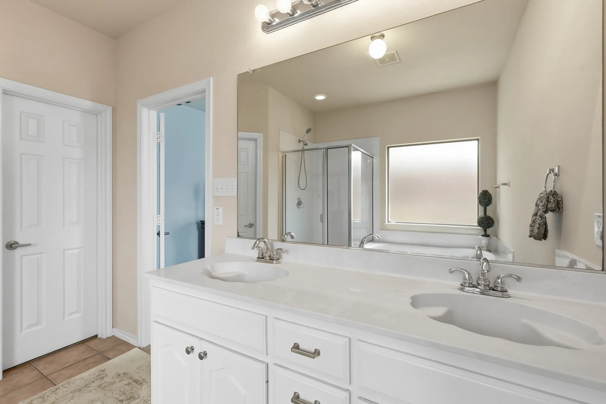 Bathroom featuring a double vanity with integrated sinks, white cabinetry, and brushed nickel fixtures