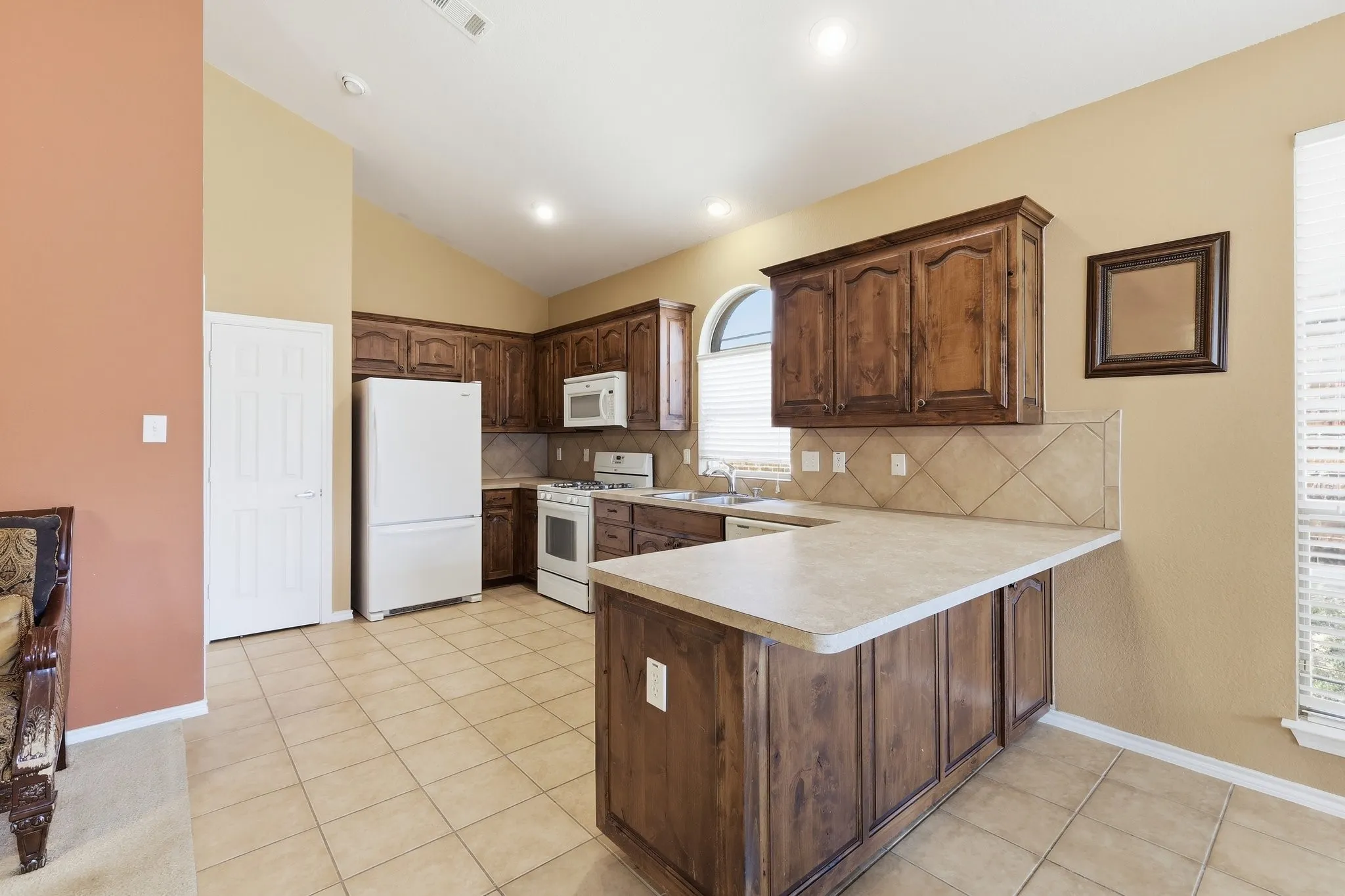 Kitchen featuring wood-finish cabinetry, a tiled backsplash, and light-toned countertops