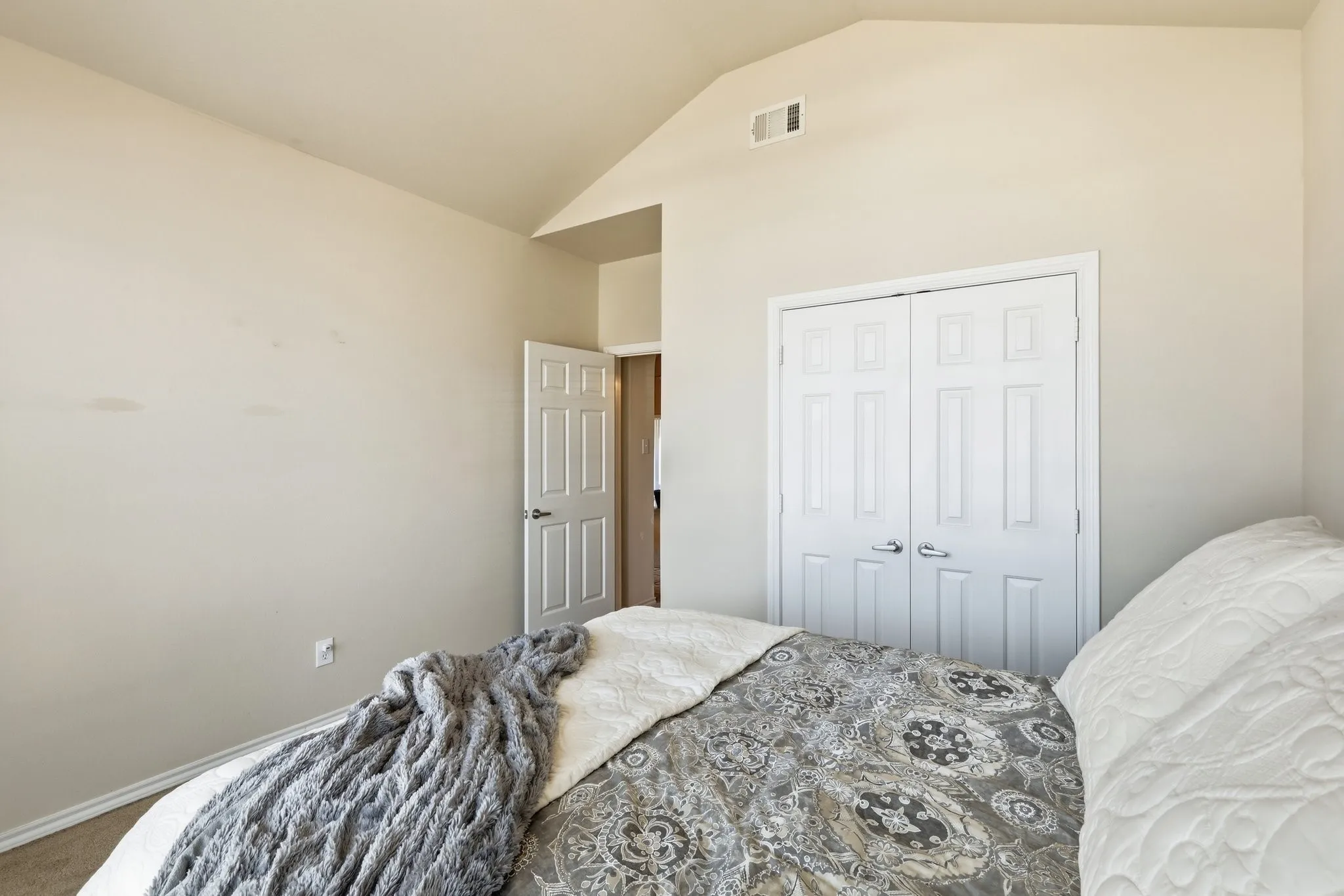 Interior bedroom featuring vaulted ceilings, neutral wall tones, and carpet flooring