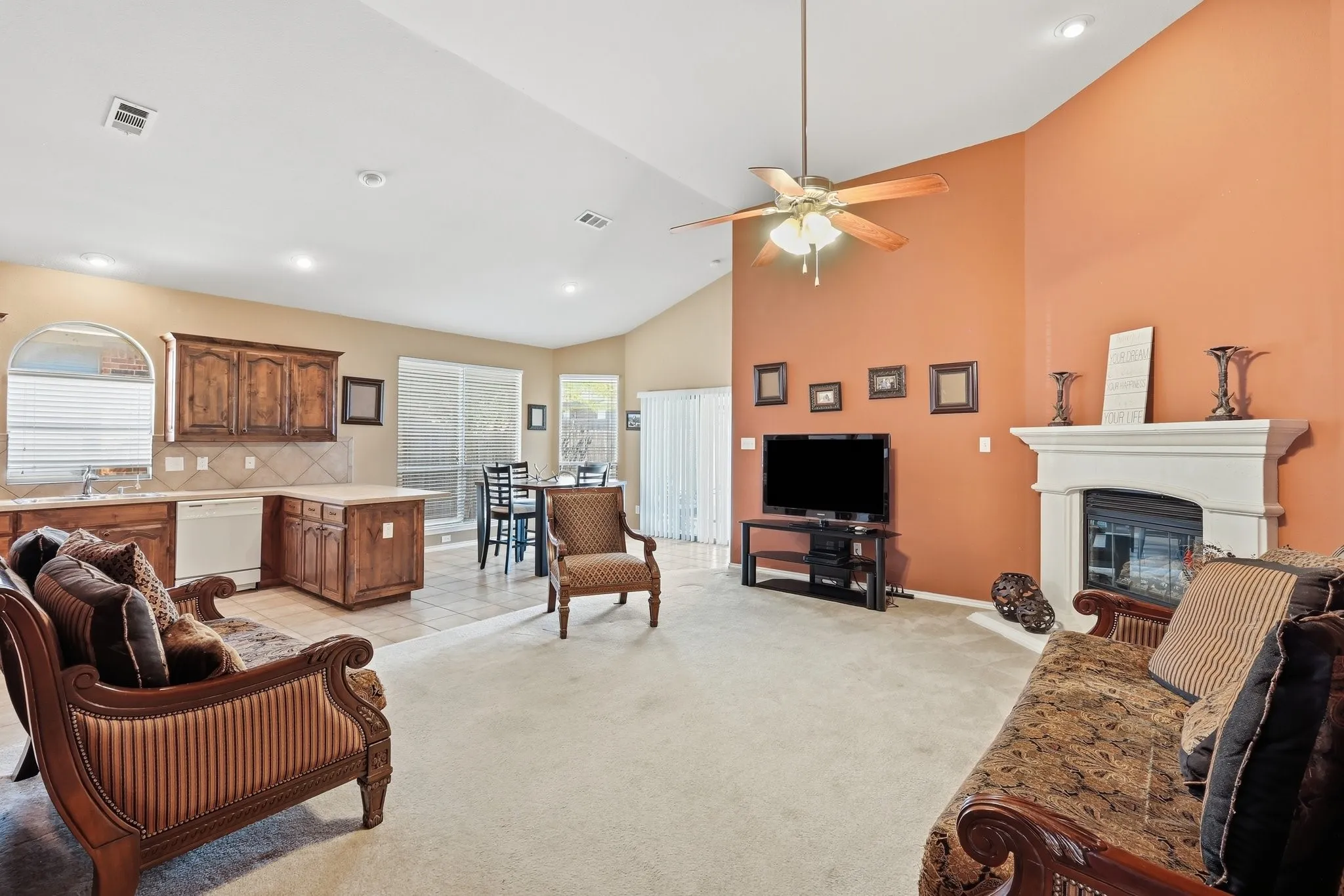 Vaulted ceiling living area featuring a fireplace with a white mantel, a ceiling fan, recessed lighting, and a sliding glass door