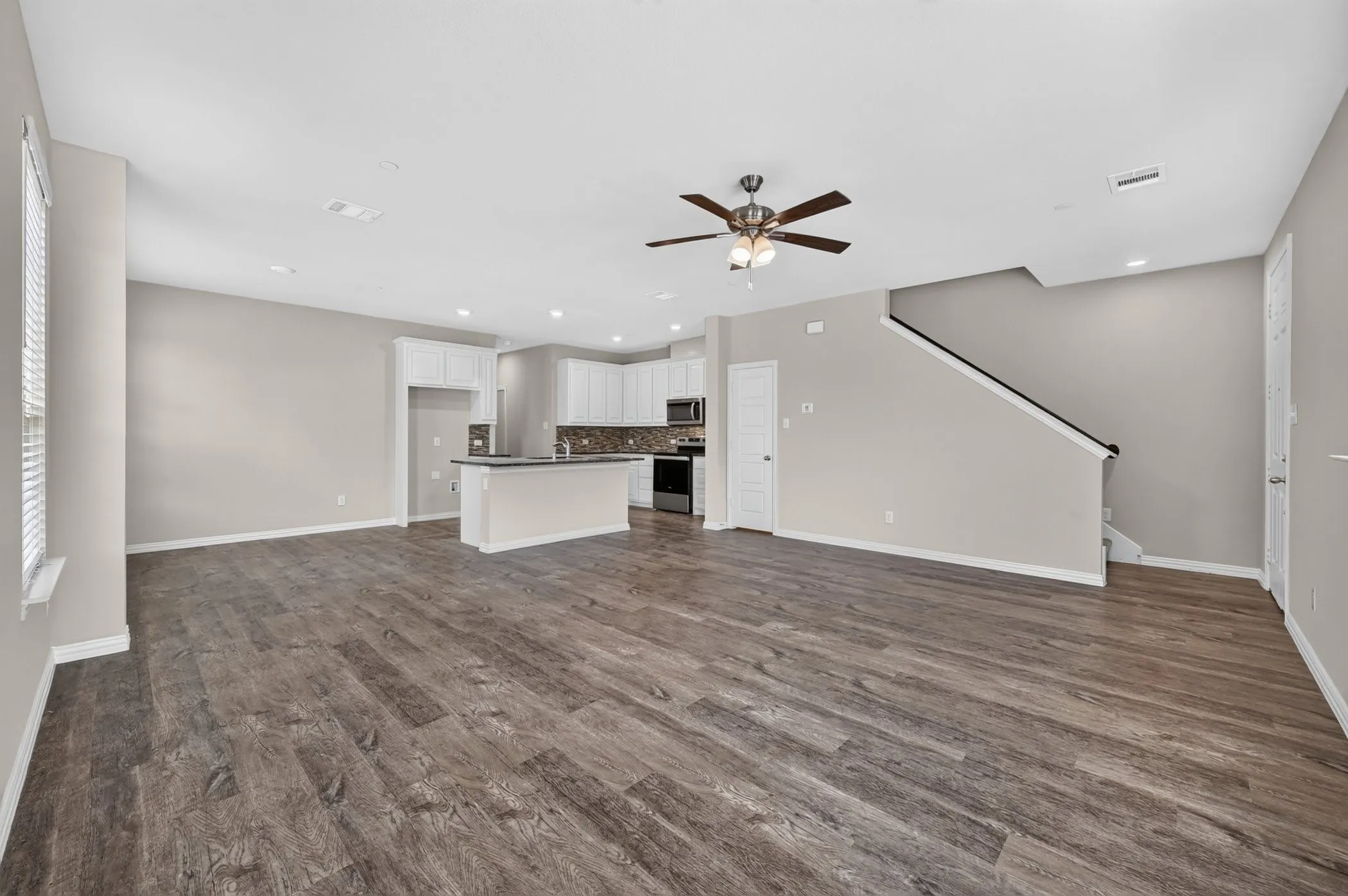 Expansive open concept living area featuring wood-finish flooring, recessed lighting, and a ceiling fan