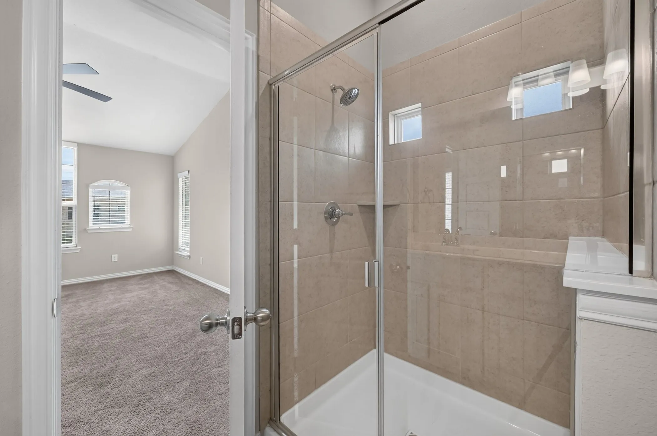 Glass-enclosed shower featuring large format tile, built-in shelf, and chrome fixtures