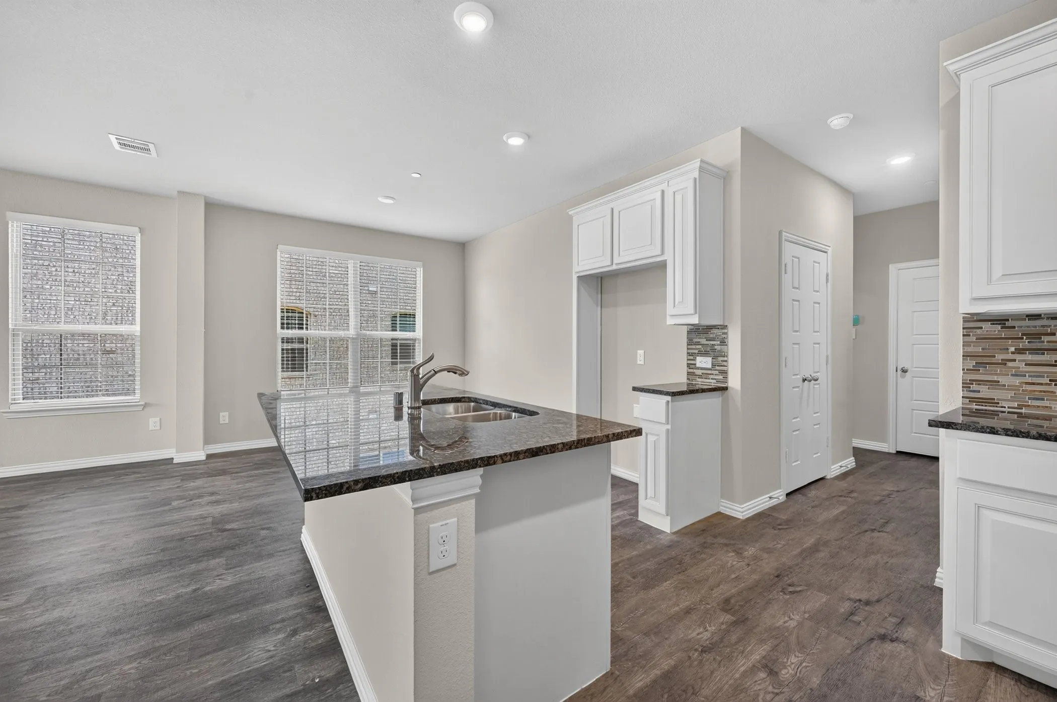 Kitchen island featuring a double-basin sink and dark granite countertop