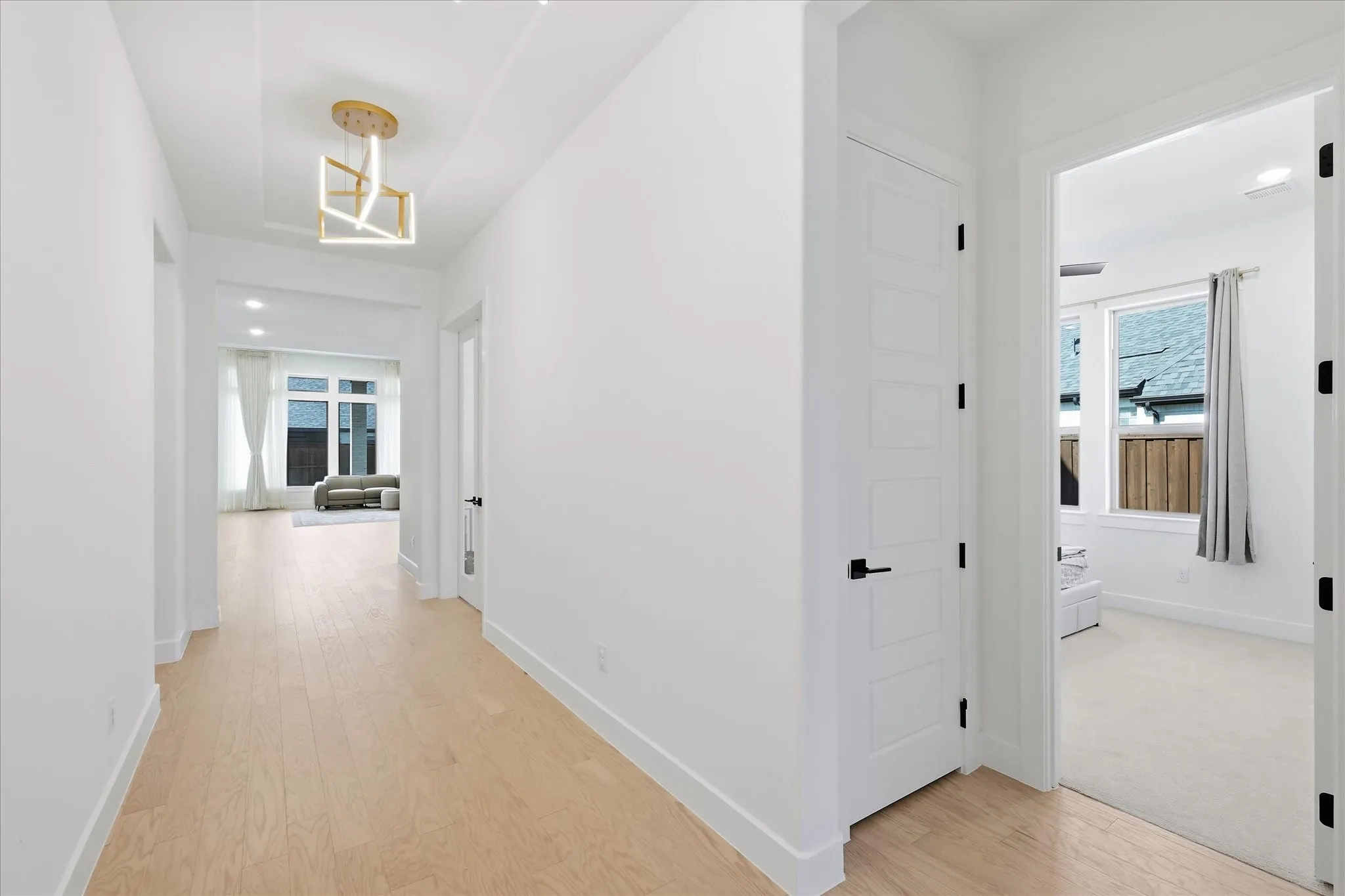 Hallway featuring wood-finish flooring, white walls, and a contemporary ceiling fixture