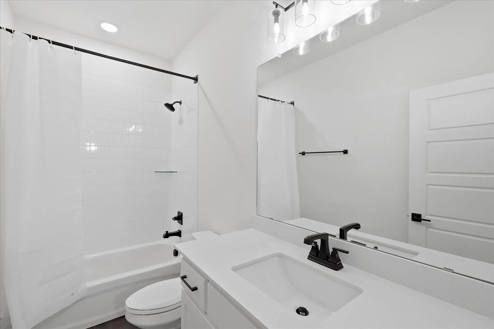 Modern bathroom featuring a spacious vanity with an undermount sink, quartz countertop, and matte black faucet hardware