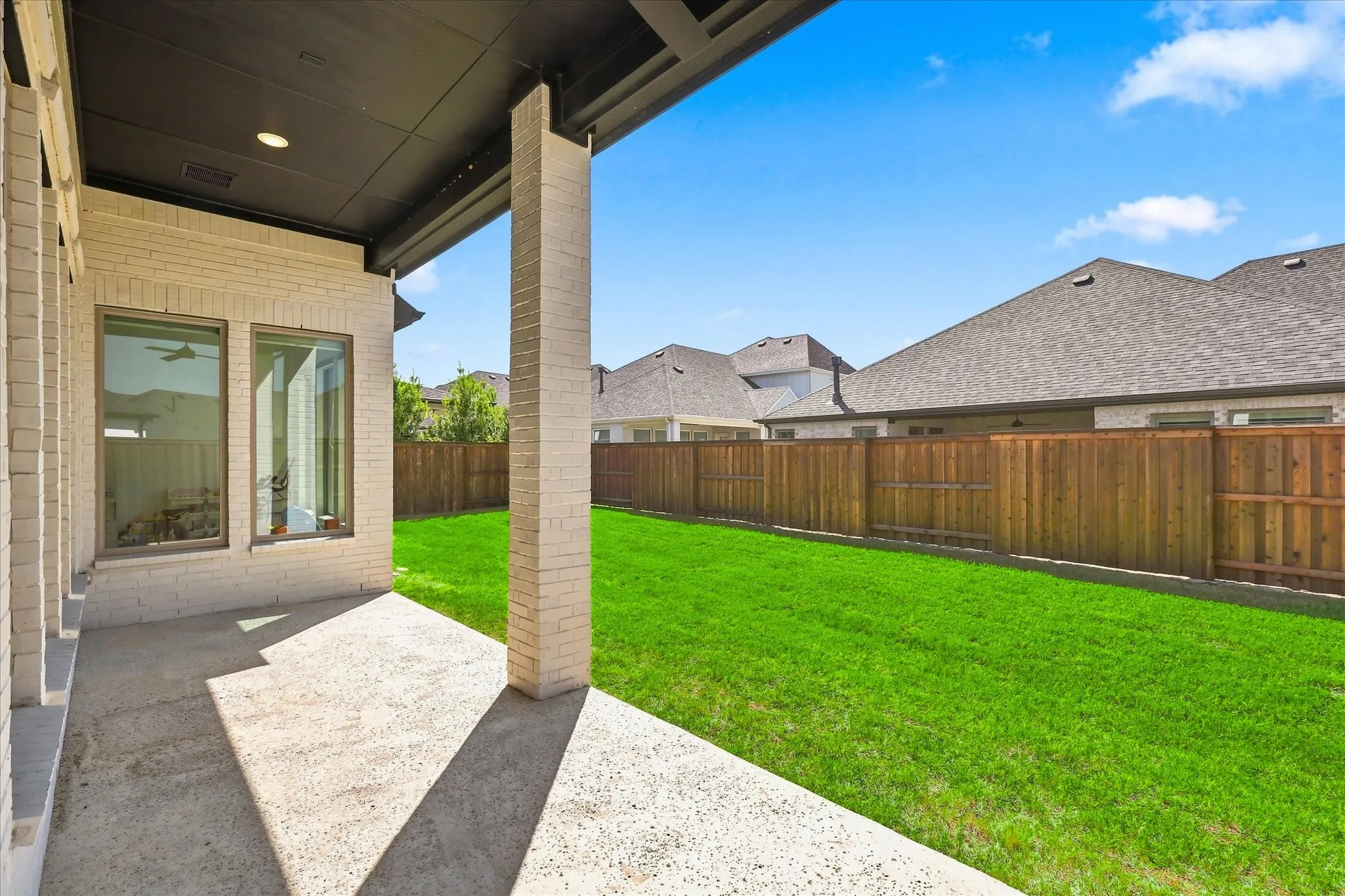 Spacious backyard featuring a manicured lawn, wood-finish privacy fencing, and mature landscaping