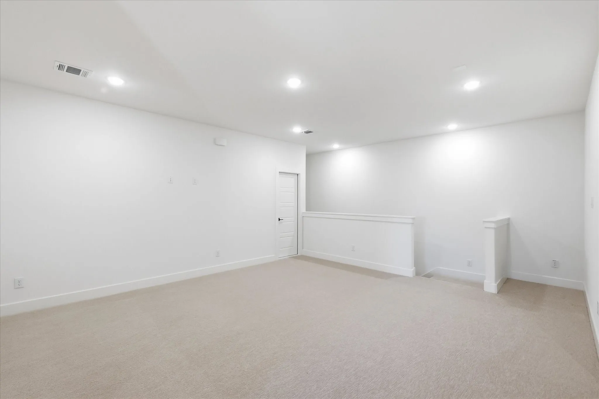 Recessed ceiling lighting, light-toned carpeting, white walls, and a white interior door