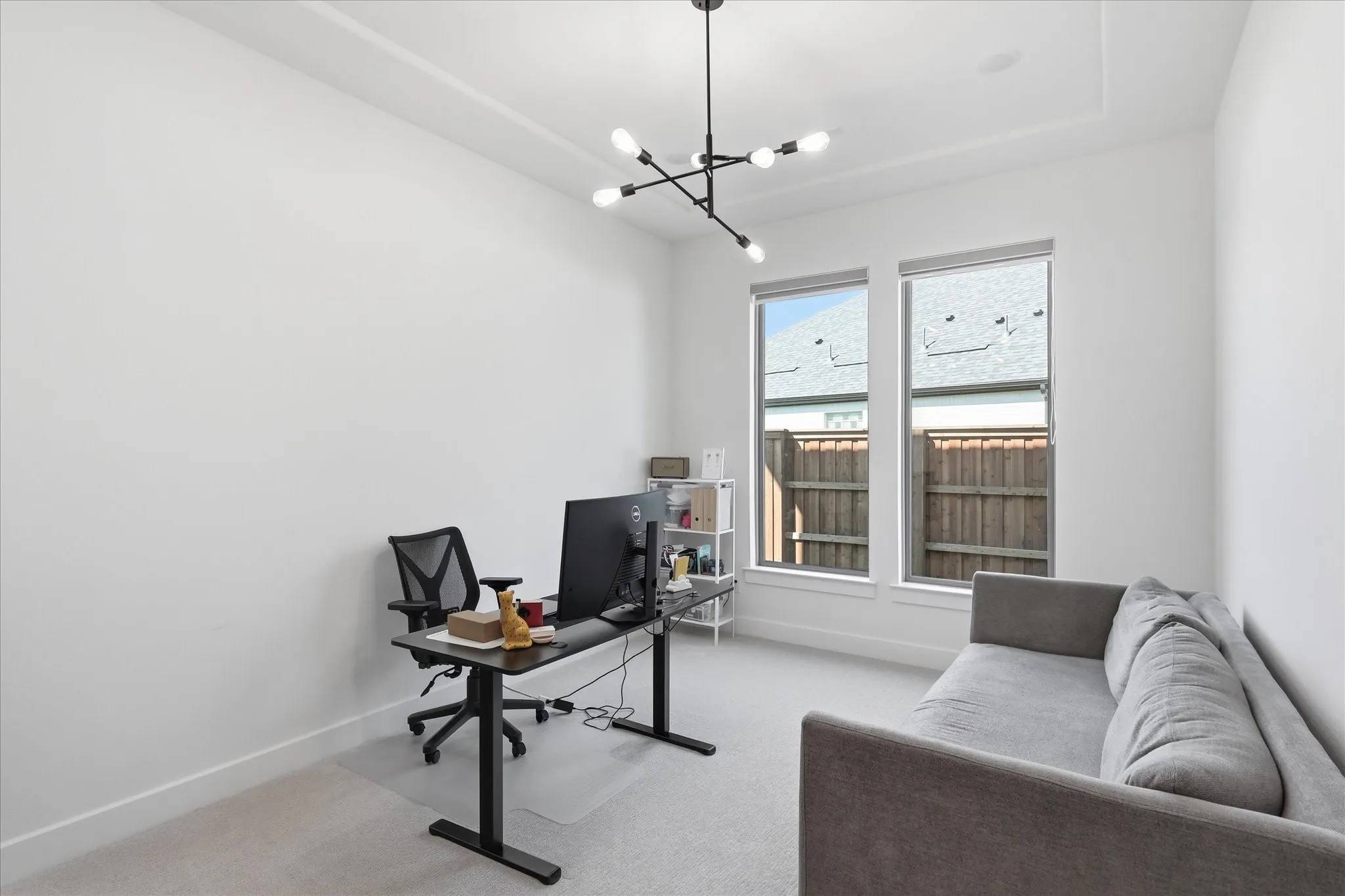 Bright, light-filled office space featuring floor-to-ceiling dual-pane windows with exterior views, neutral carpet flooring, and a modern pendant light fixture