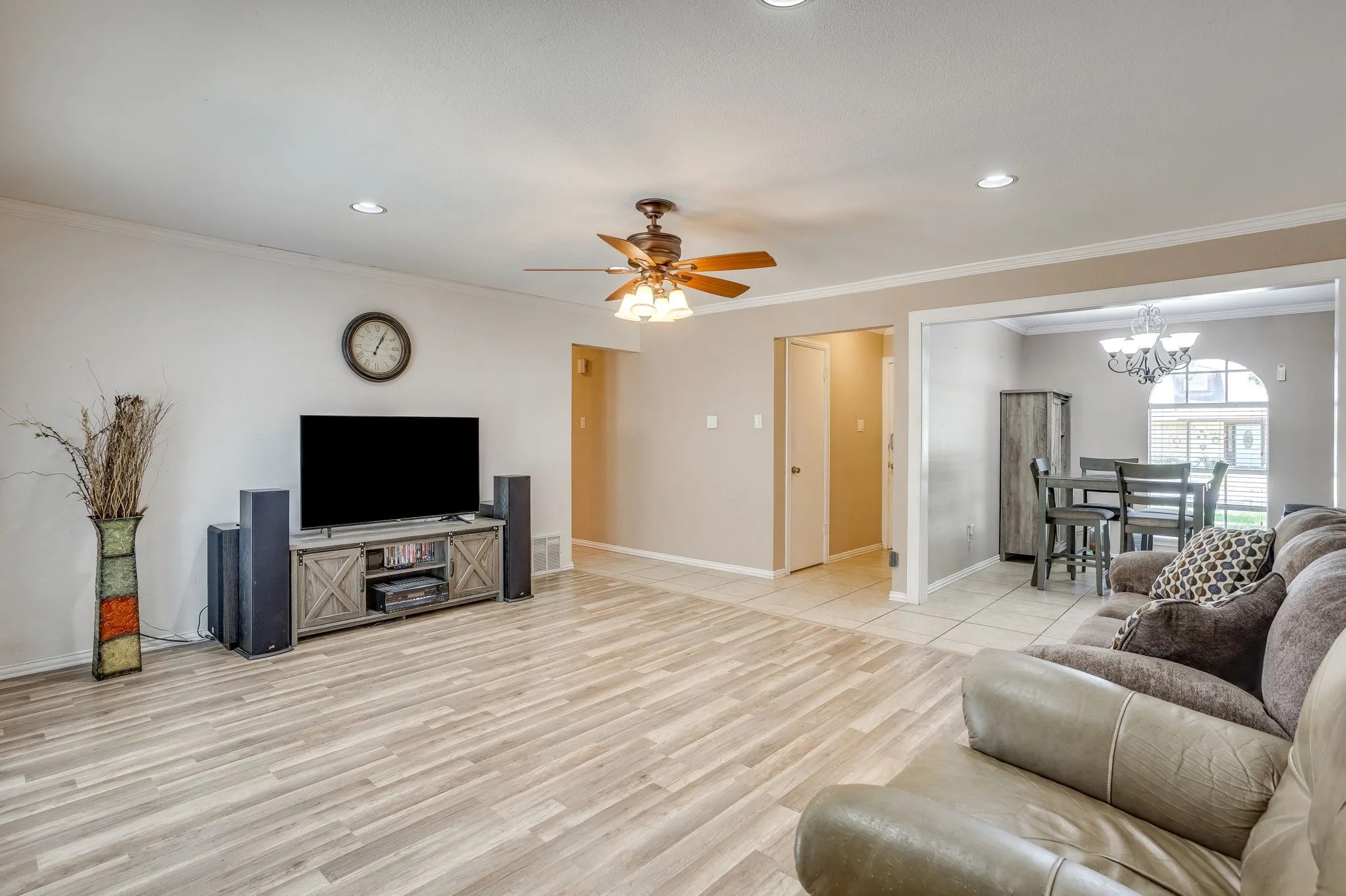 Spacious open-concept living area showcasing wood-finish flooring, recessed lighting, and a ceiling fan with integrated light fixture