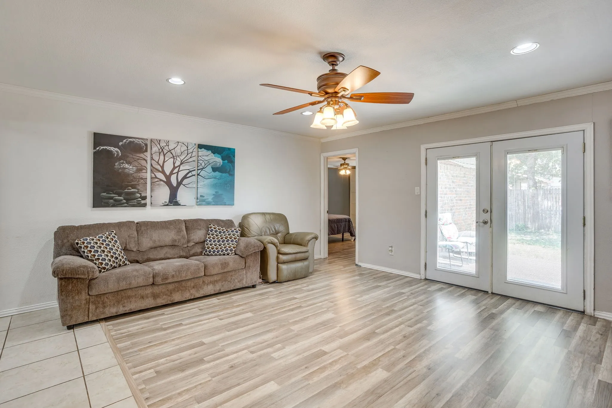 Bright and spacious living area featuring wood-finish flooring throughout, recessed lighting, and a ceiling fan with integrated light fixture