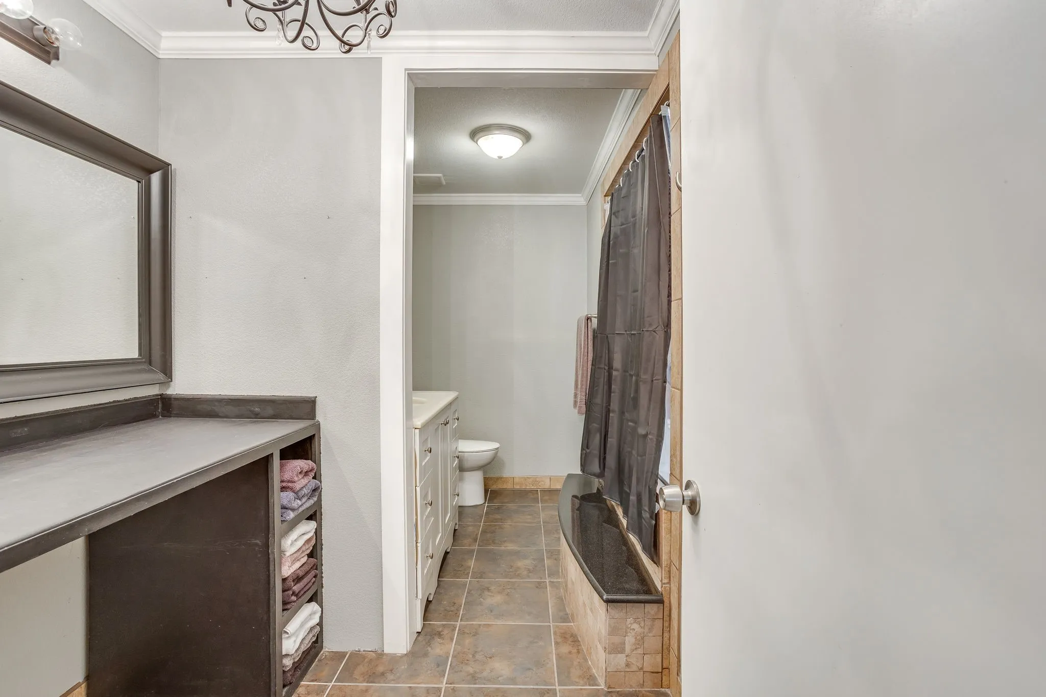 Bathroom featuring a built-in vanity with open shelving, a framed mirror, and crown molding