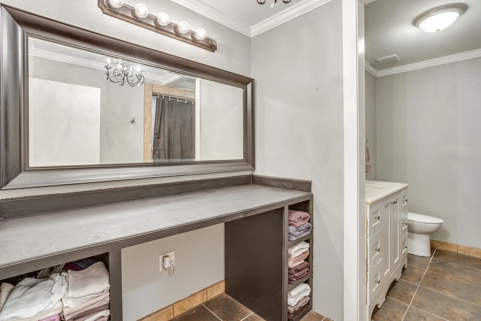 Spa-inspired master bath featuring an expansive dual-sink vanity with white cabinetry, wood-finish flooring, and abundant storage