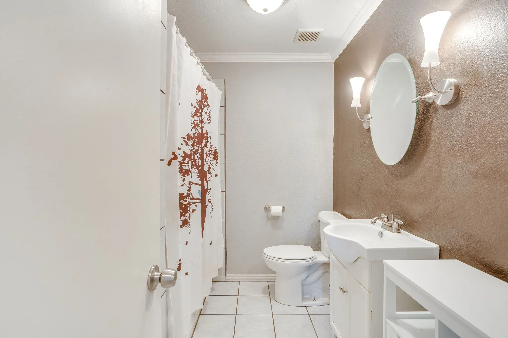 Full bathroom featuring a white vanity with integrated sink, chrome faucet, oval mirror, and a two-light sconce