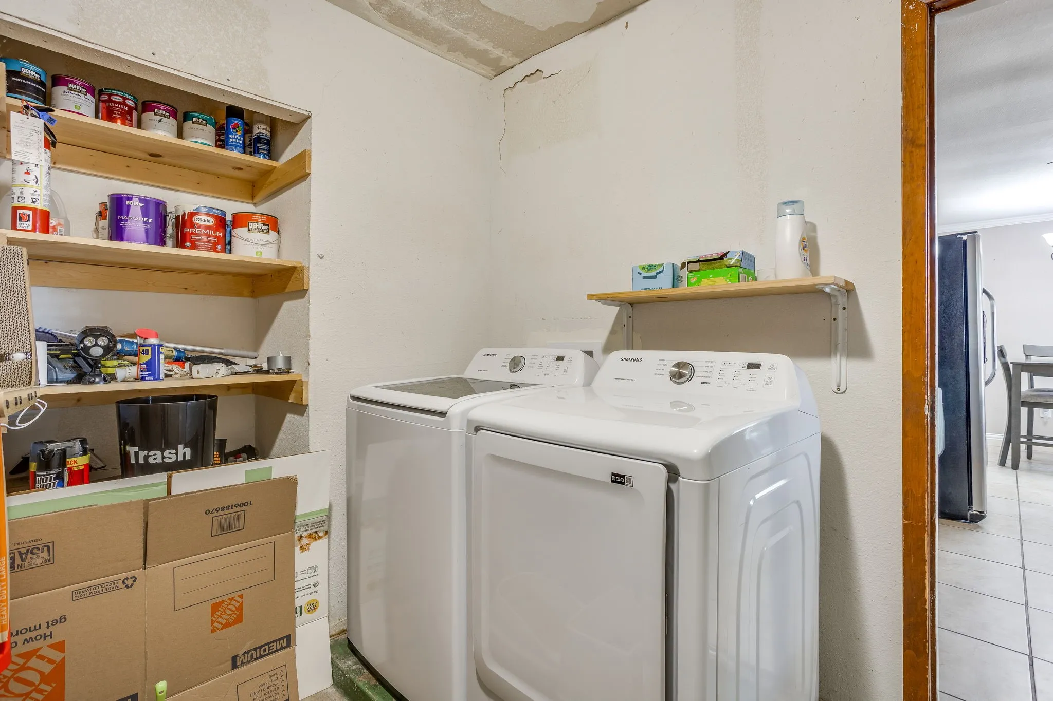 Dedicated laundry area featuring a built-in shelving unit, a wall-mounted floating shelf, and durable tile flooring
