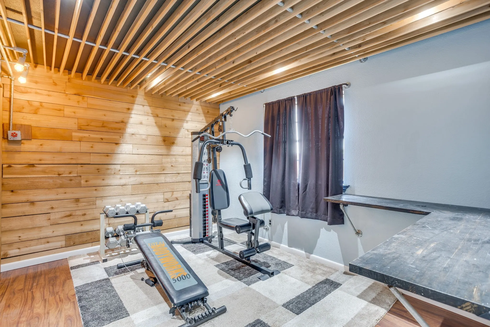Dedicated fitness room featuring a multi-station exercise machine, adjustable weight bench, and stationary bike