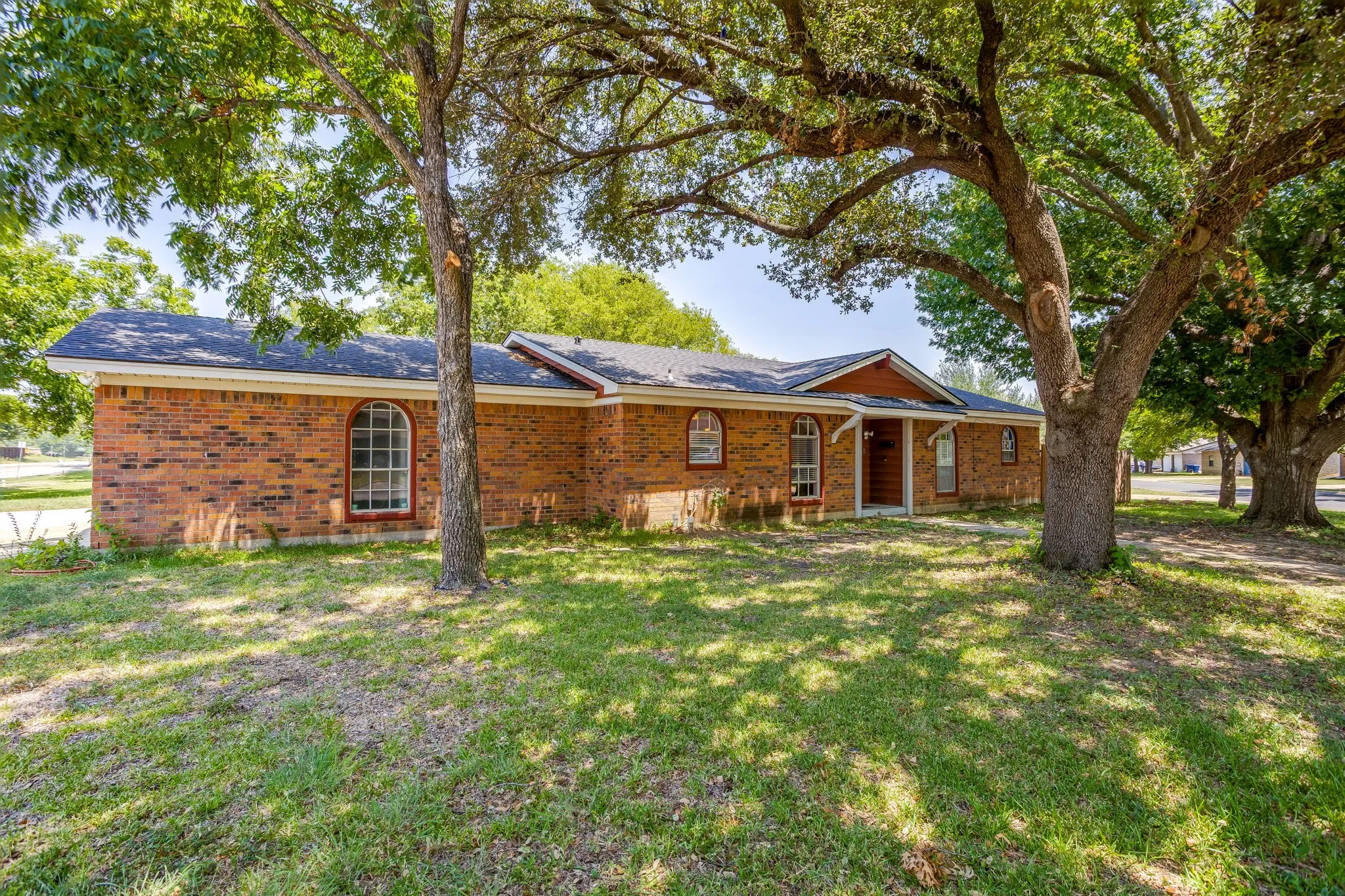 Charming brick ranch home nestled beneath mature shade trees on a spacious lot