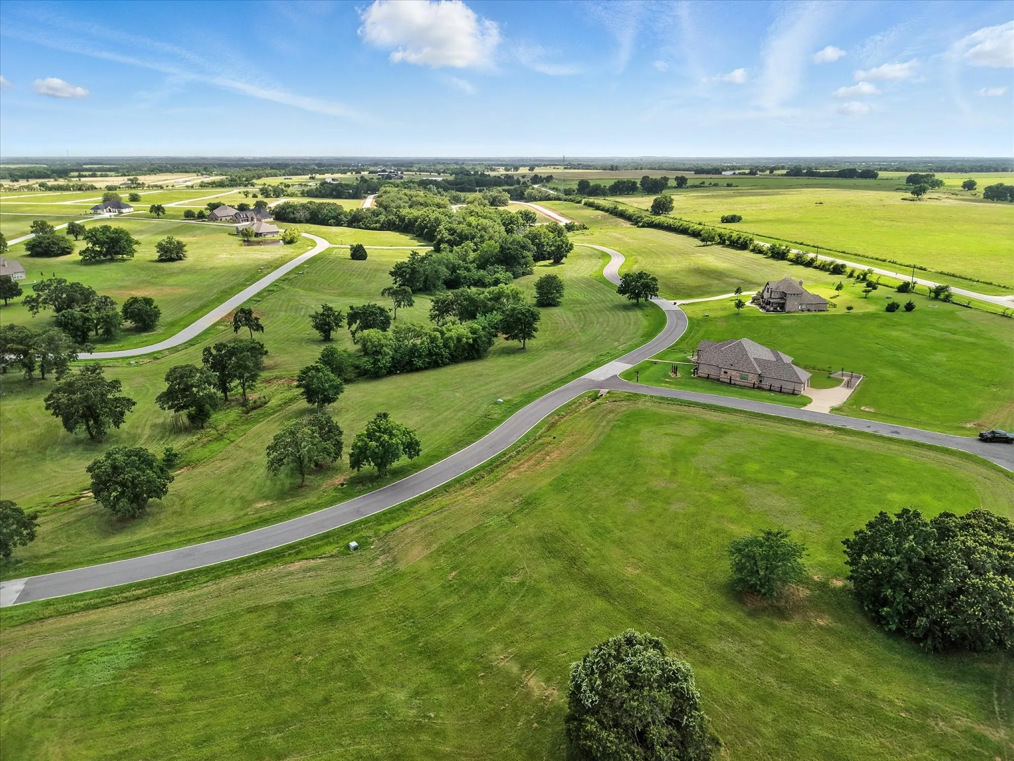Sprawling rural estate showcasing lush pastoral grounds with mature tree clusters, gently winding private driveway, and multiple residential structures set across expansive acreage
