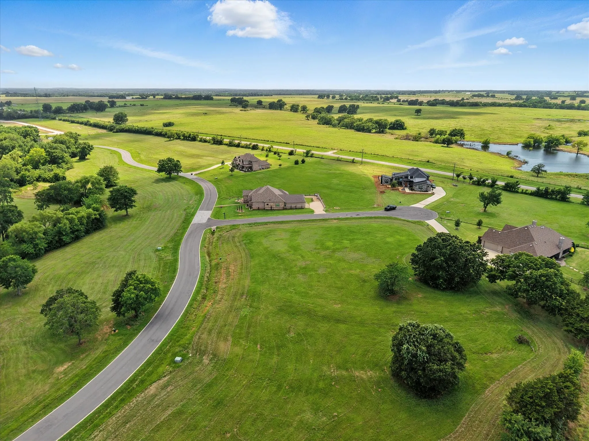 Sprawling rural estate featuring multiple brick residences set on manicured grounds with mature trees, winding driveway, and pastoral landscape