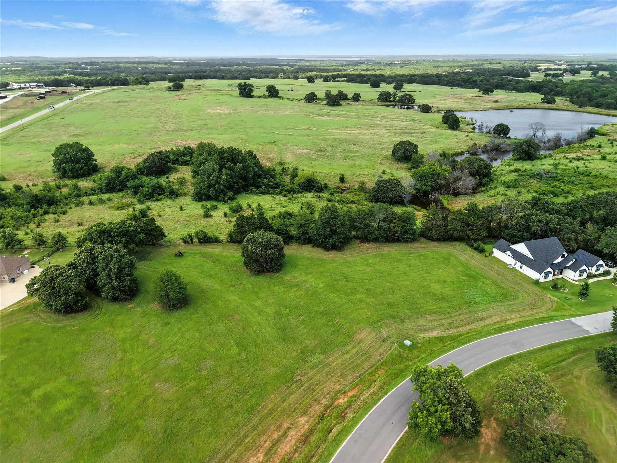 Expansive rural estate showcasing meticulously manicured grounds with mature specimen trees, rolling pastoral landscape, and a modern residence nestled within the property