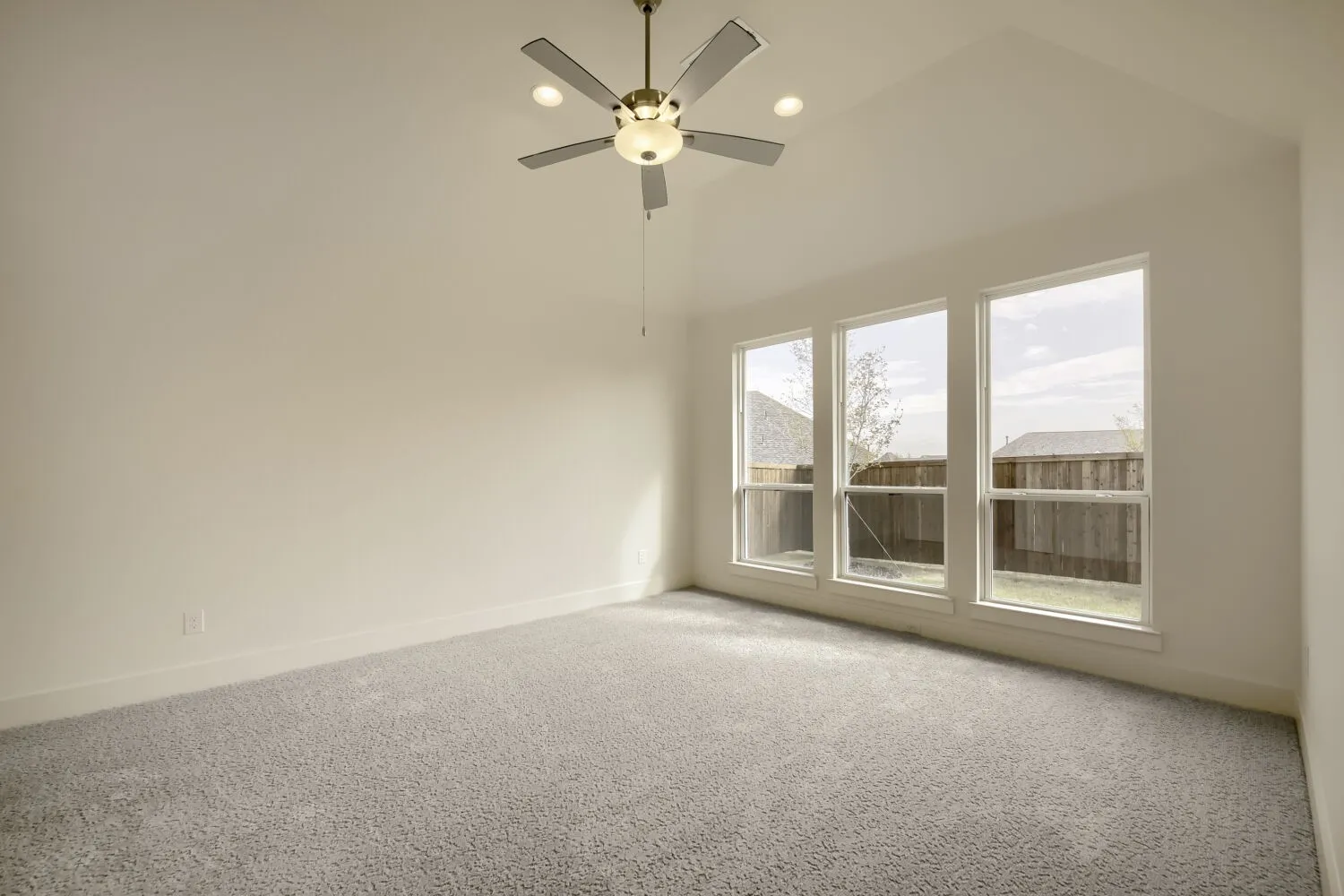 Vaulted ceiling with a ceiling fan, recessed lighting, three large windows, and carpet flooring