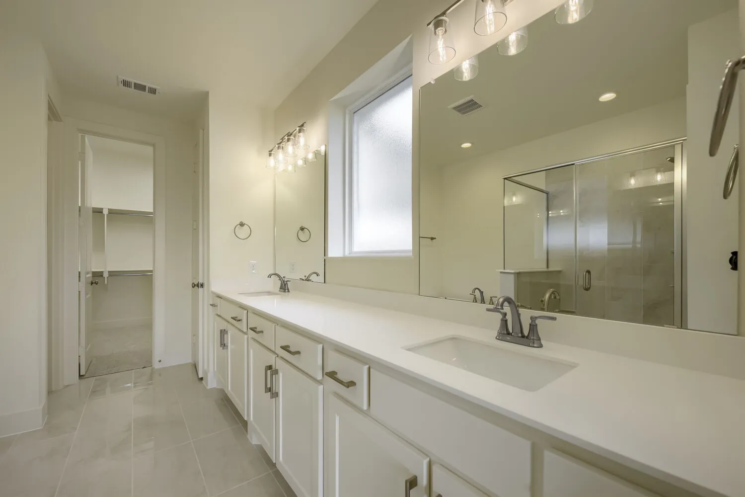 Dual sink vanity with white cabinetry, integrated sinks, and chrome fixtures