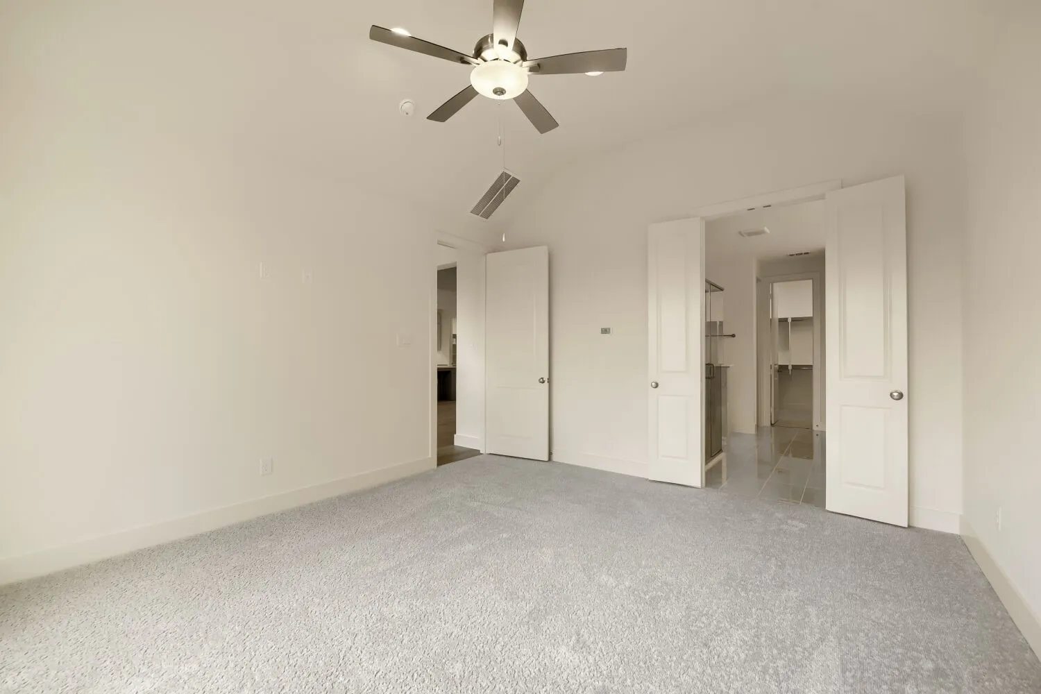 Vaulted ceiling, ceiling fan with integrated lighting, neutral carpeting, white interior doors, and custom built-in shelving