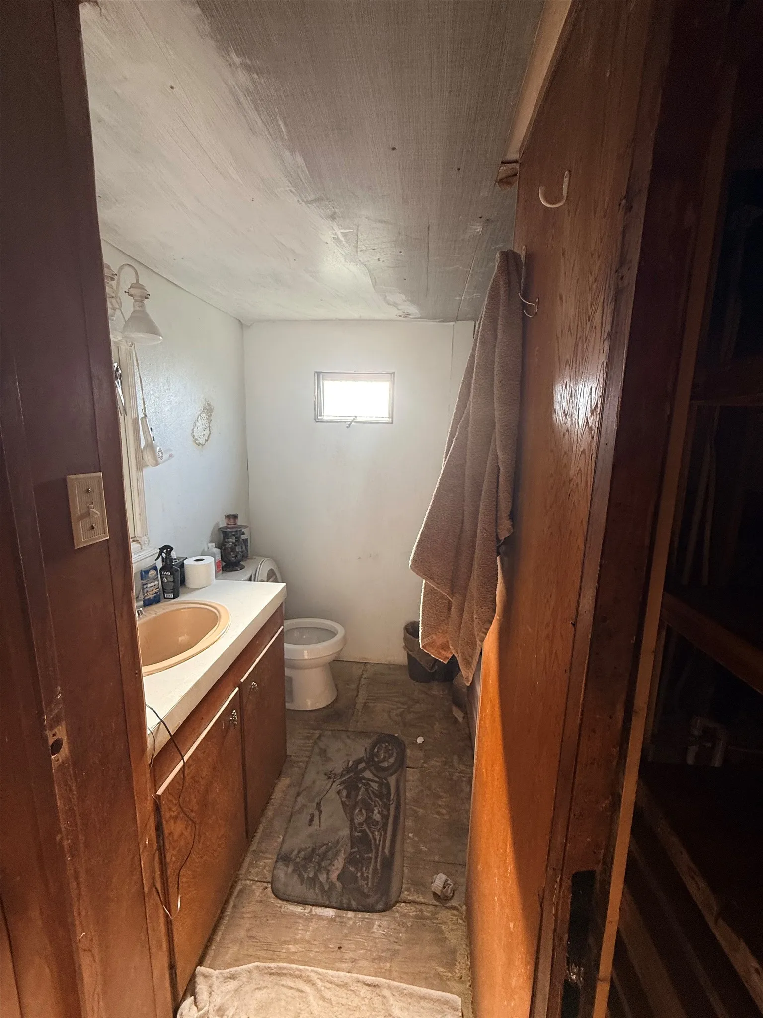 Bathroom featuring wood-finish vanity with integrated sink, toilet, and window for natural light