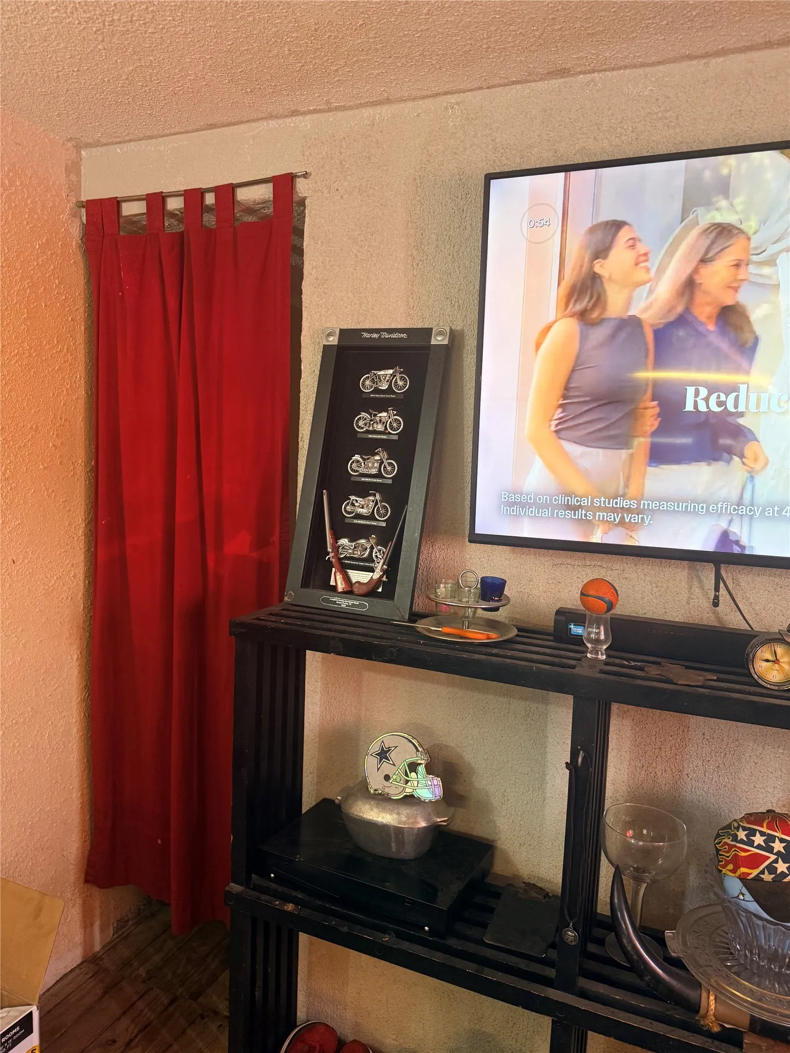 Entertaining space featuring built-in black shelving with display areas, wall-mounted flat-screen television, and red thermal curtain panels
