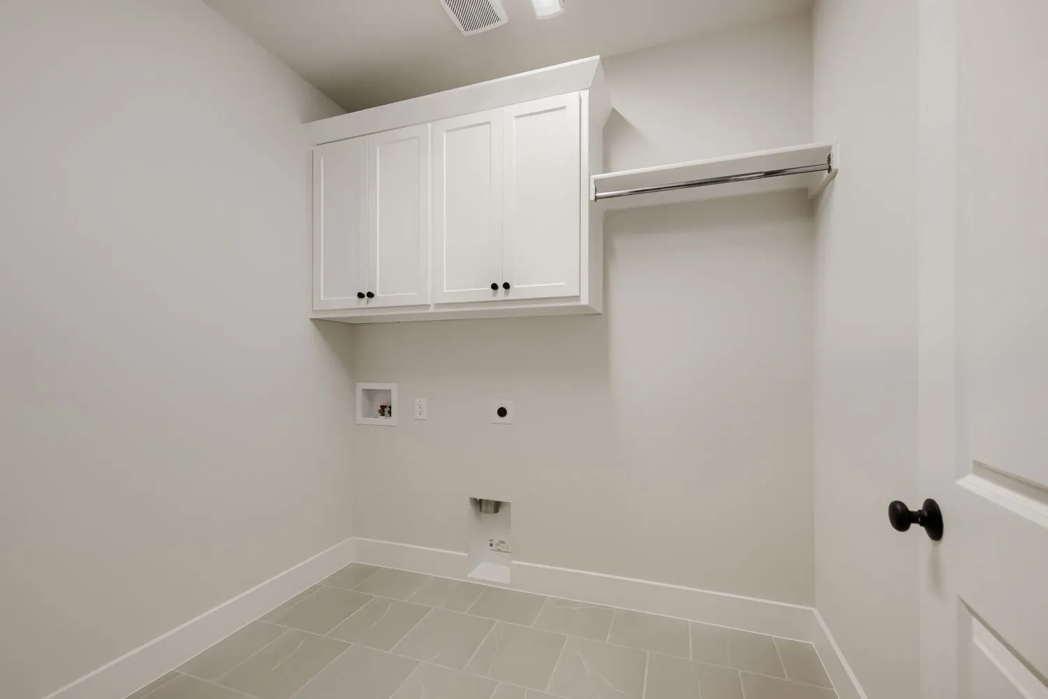 Laundry area featuring white shaker-style cabinetry, a built-in hanging rod, and tile flooring