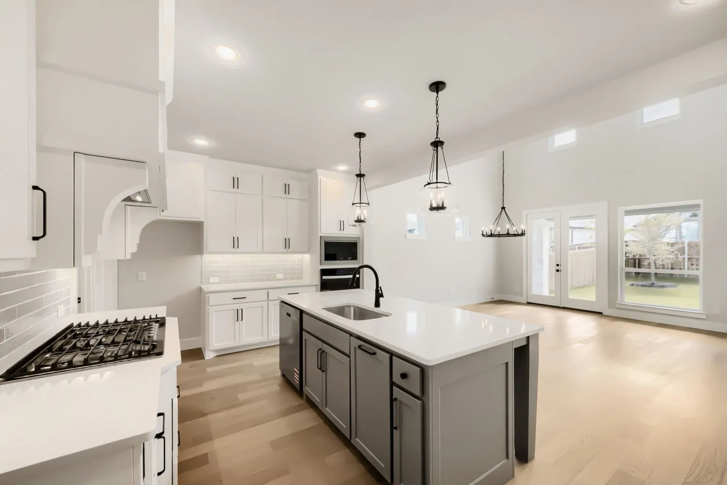 Spacious kitchen featuring white cabinetry, a large center island with a sink, stainless steel appliances, and wood-finish flooring