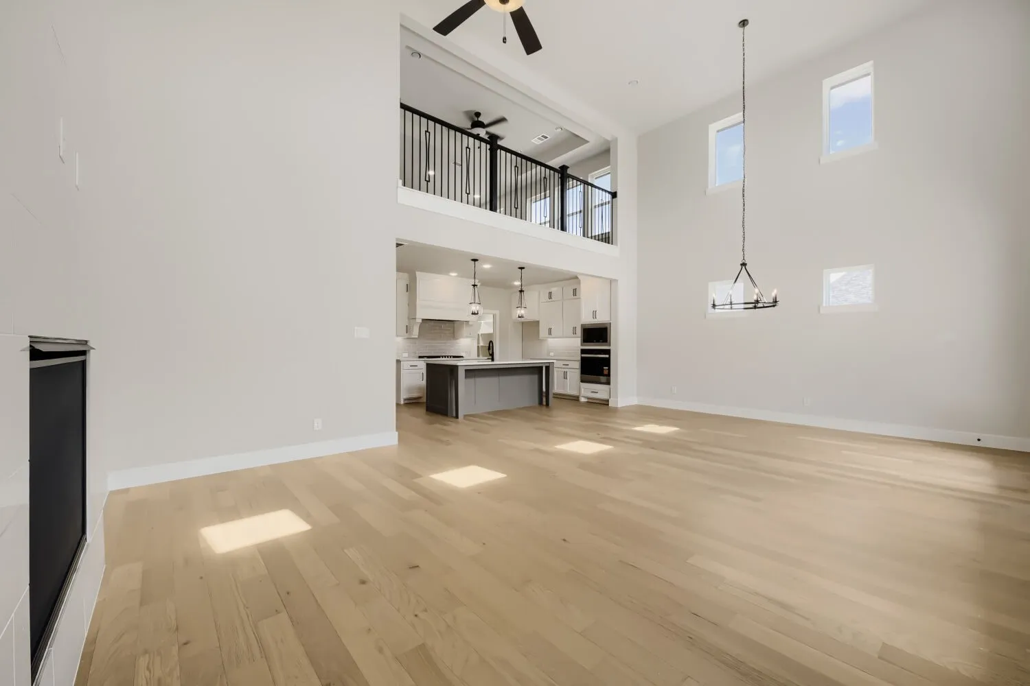 Two-story living area with high ceilings, wood-finish flooring, and a fireplace