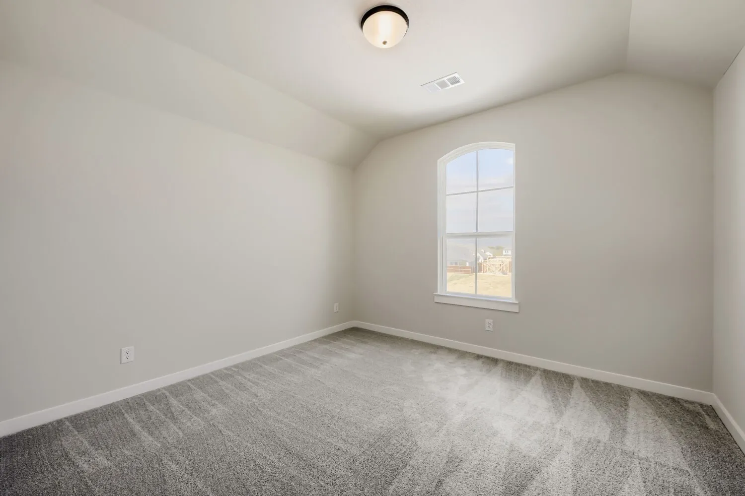 Arched window with gridded panes, vaulted ceiling, flush mount ceiling light, and wall-to-wall carpeting