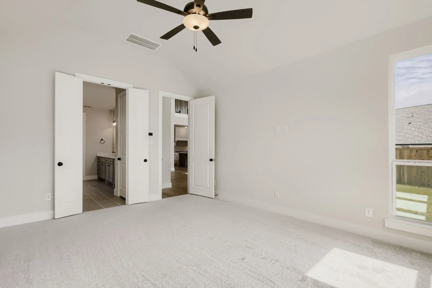 Carpeted room with vaulted ceiling and ceiling fan